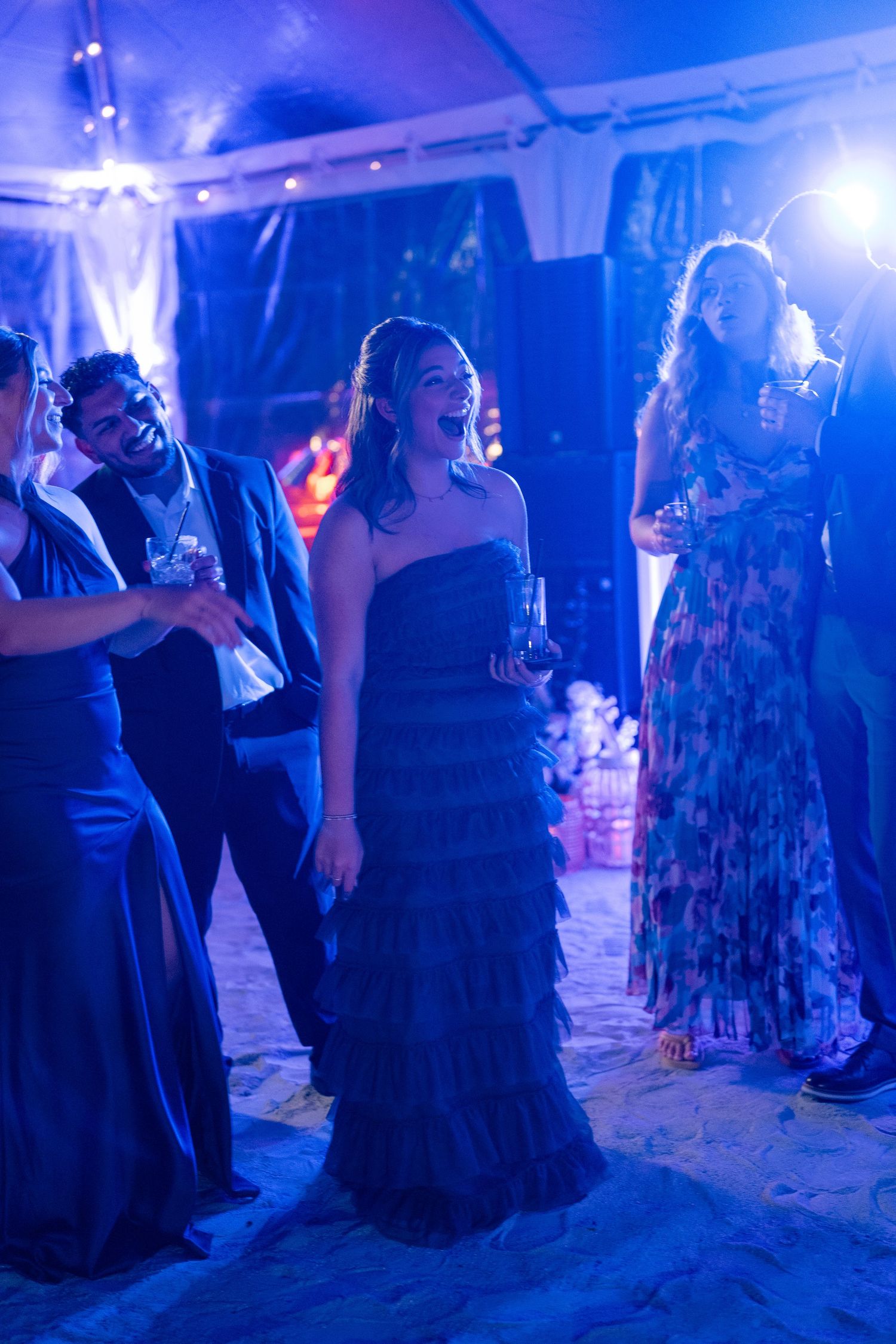 Wedding guests dancing under blue lighting at an evening reception.