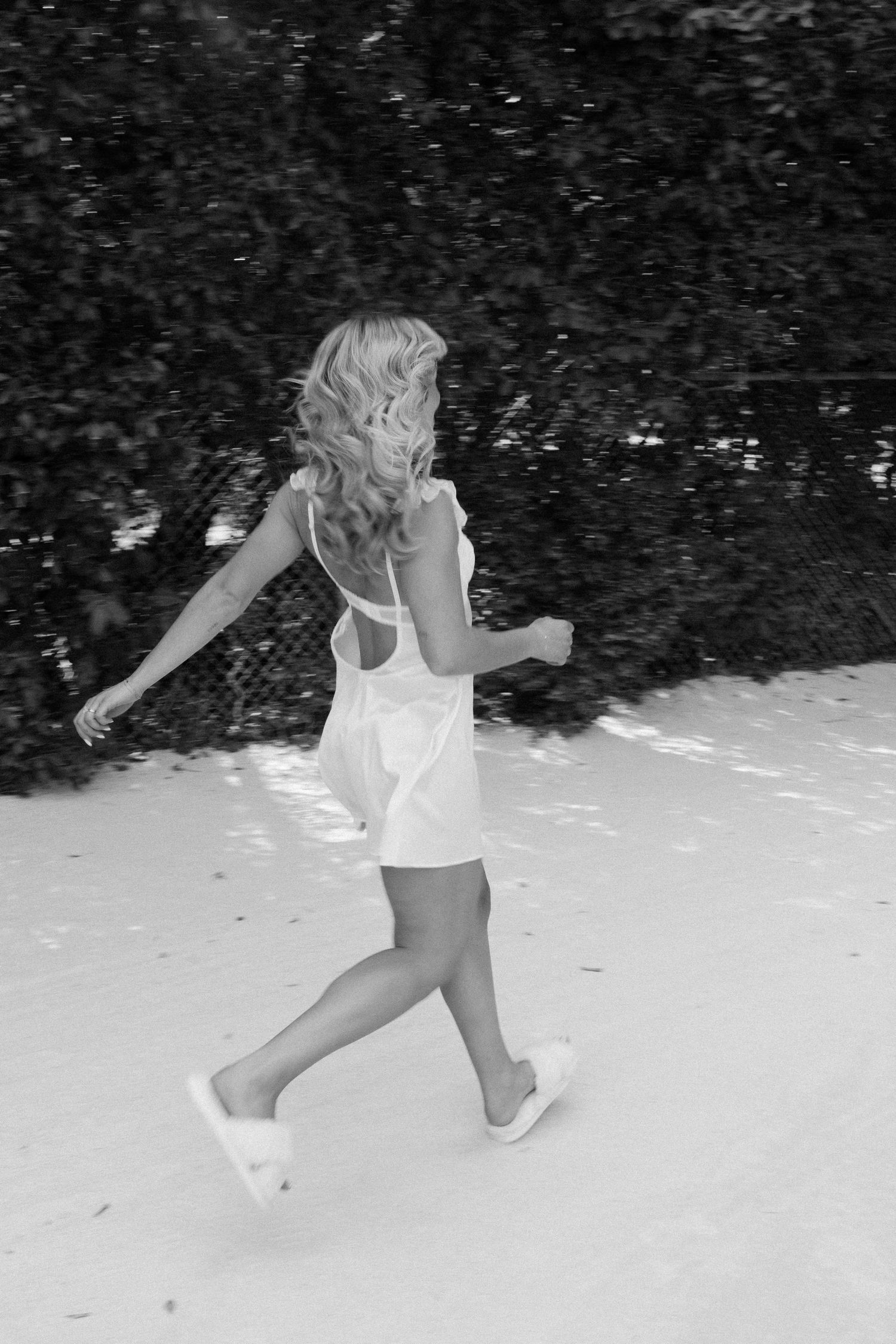 Sequence of a person running and jumping playfully in the snow wearing white clothing.