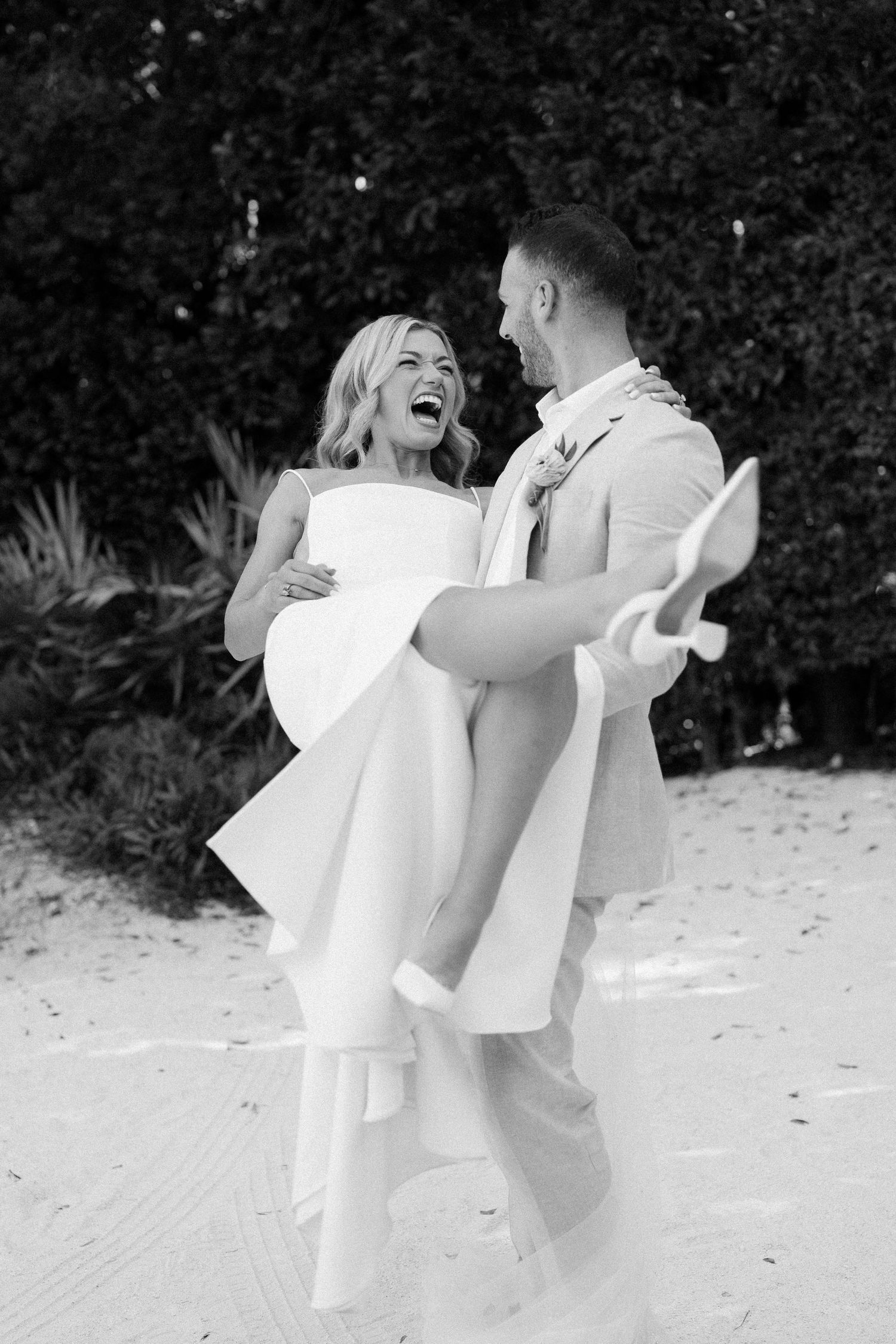 A joyful couple in white attire dancing and spinning outdoors.
