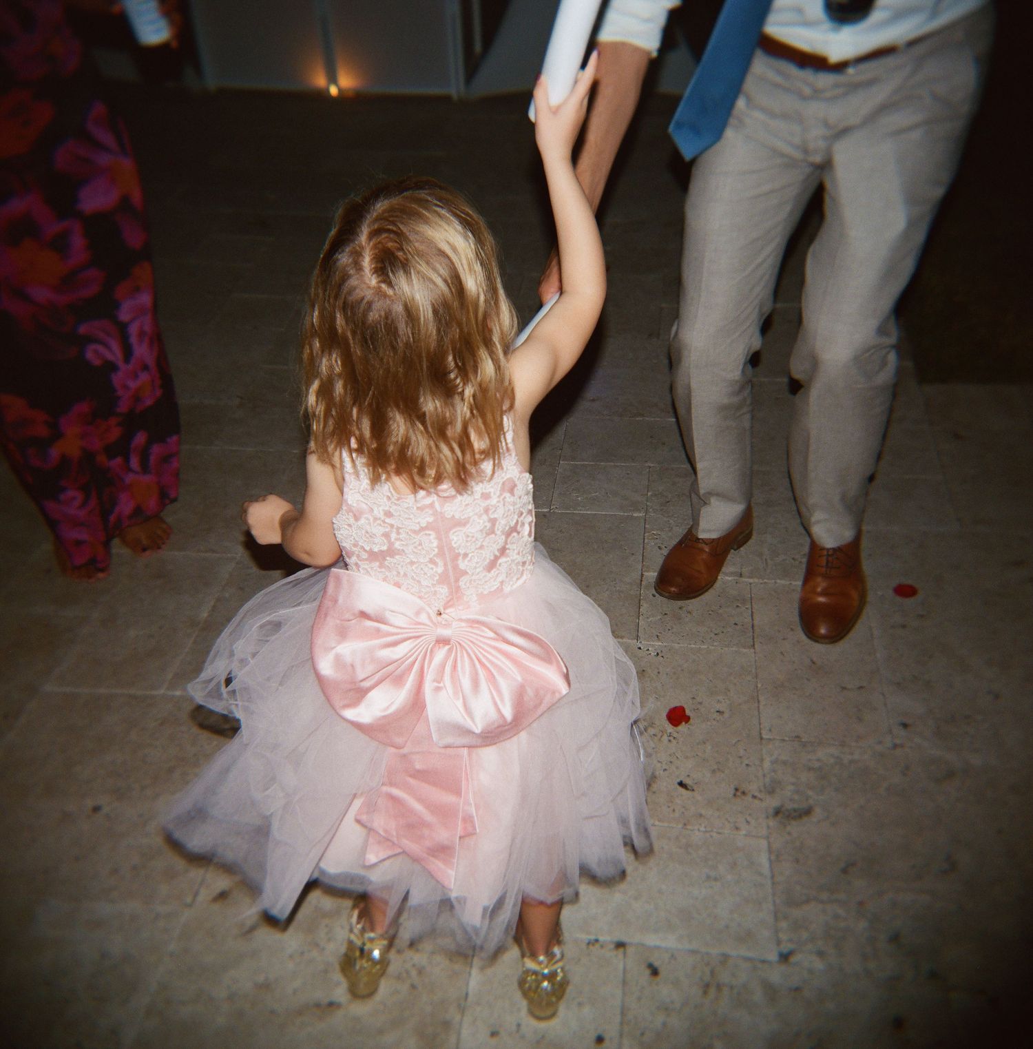 Young girl in pink dress with bow twirling on dance floor.