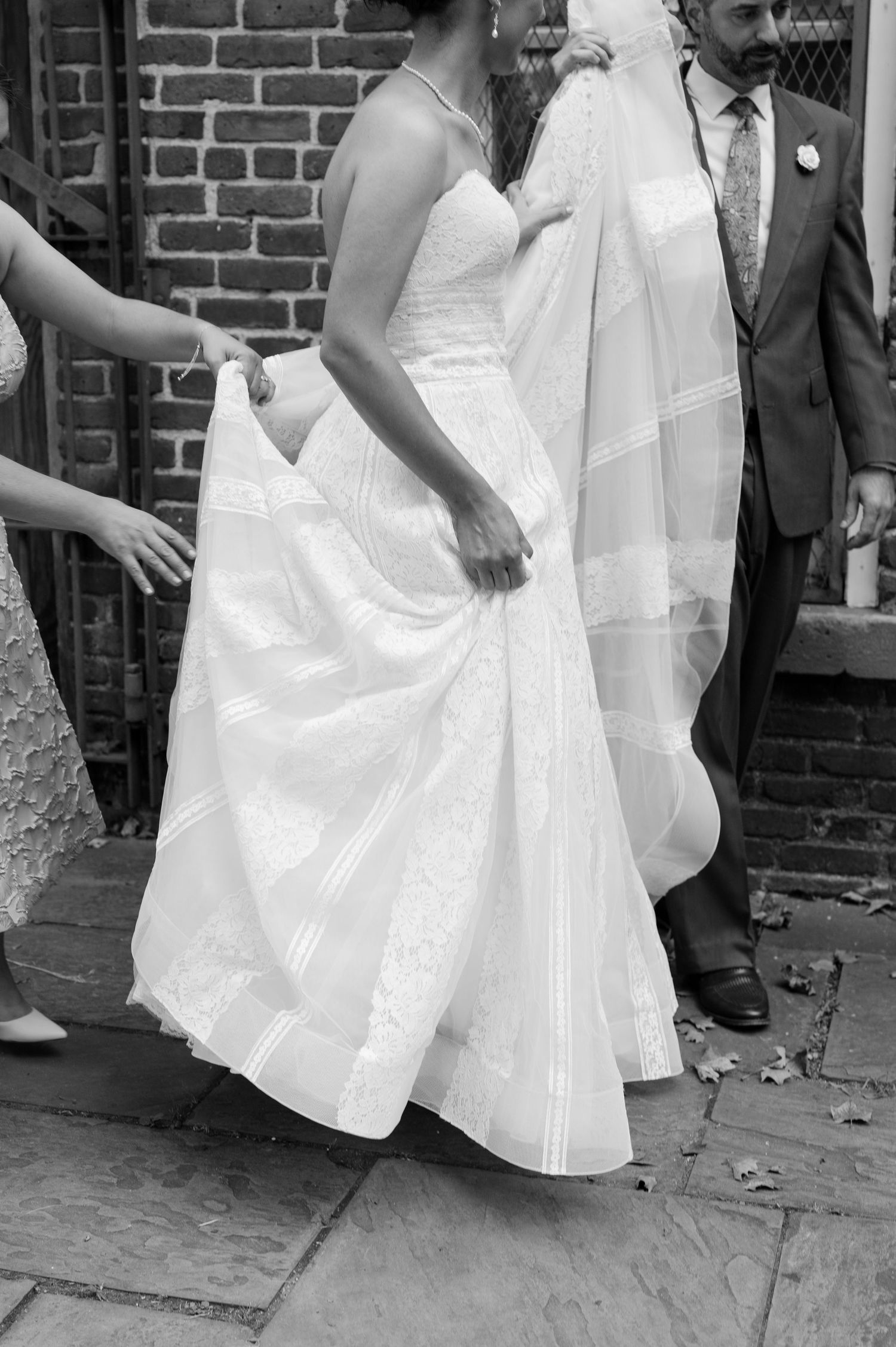 A series of black and white photos showing a woman in a white dress twirling and dancing on a brick-lined street.