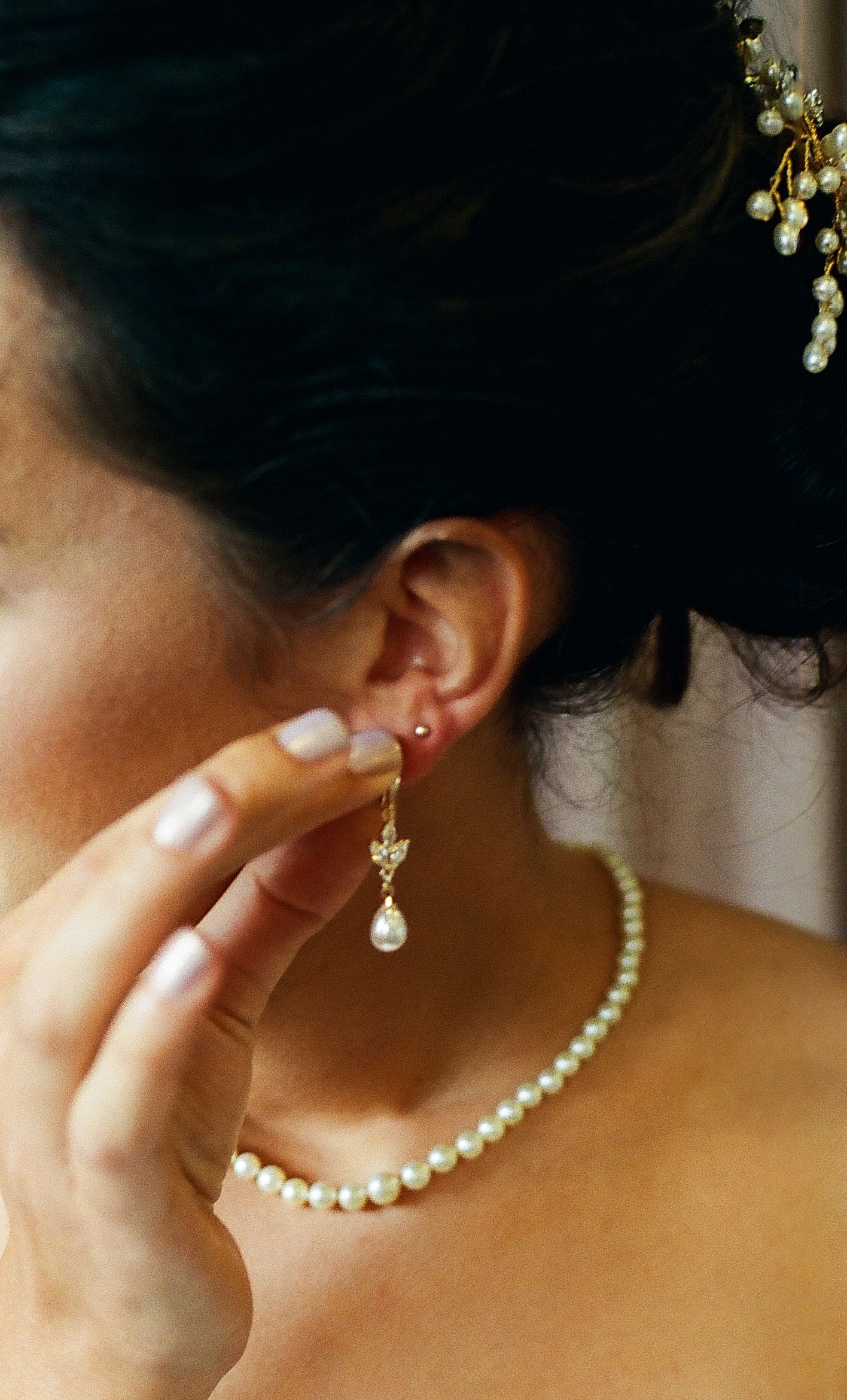 A close-up sequence of pearl earrings being worn, showing different angles against warm skin tones in soft lighting.