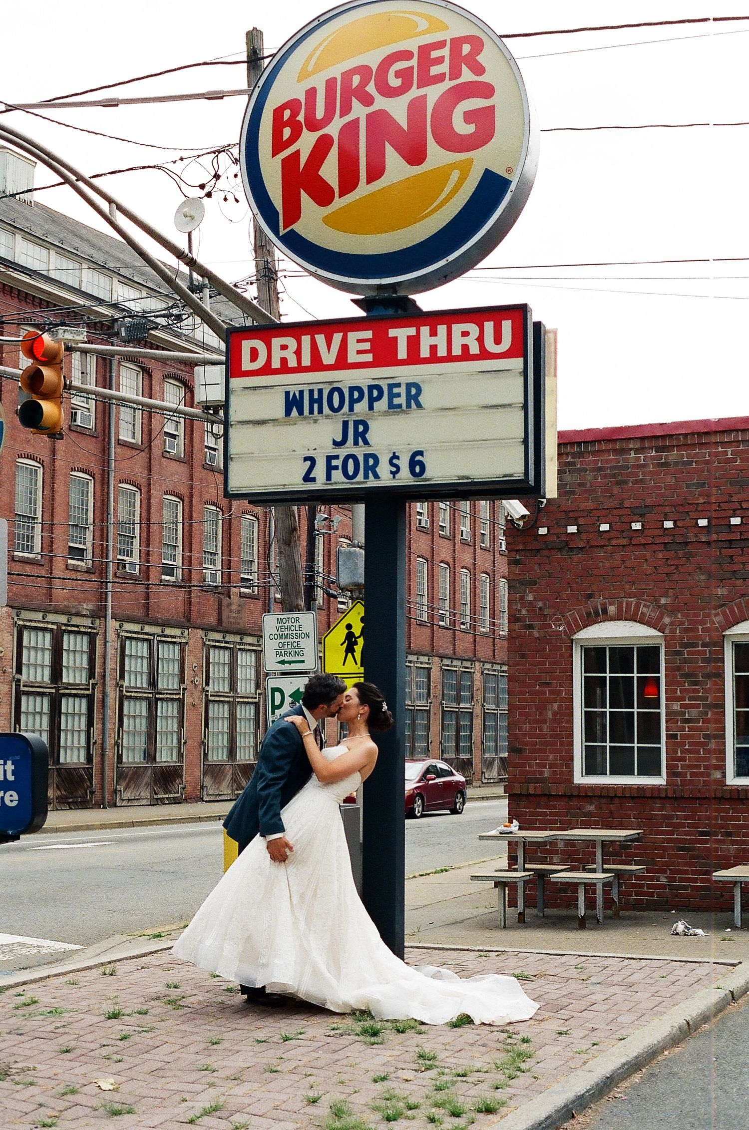 A creative wedding photo taken in front of a Burger King drive-thru sign.