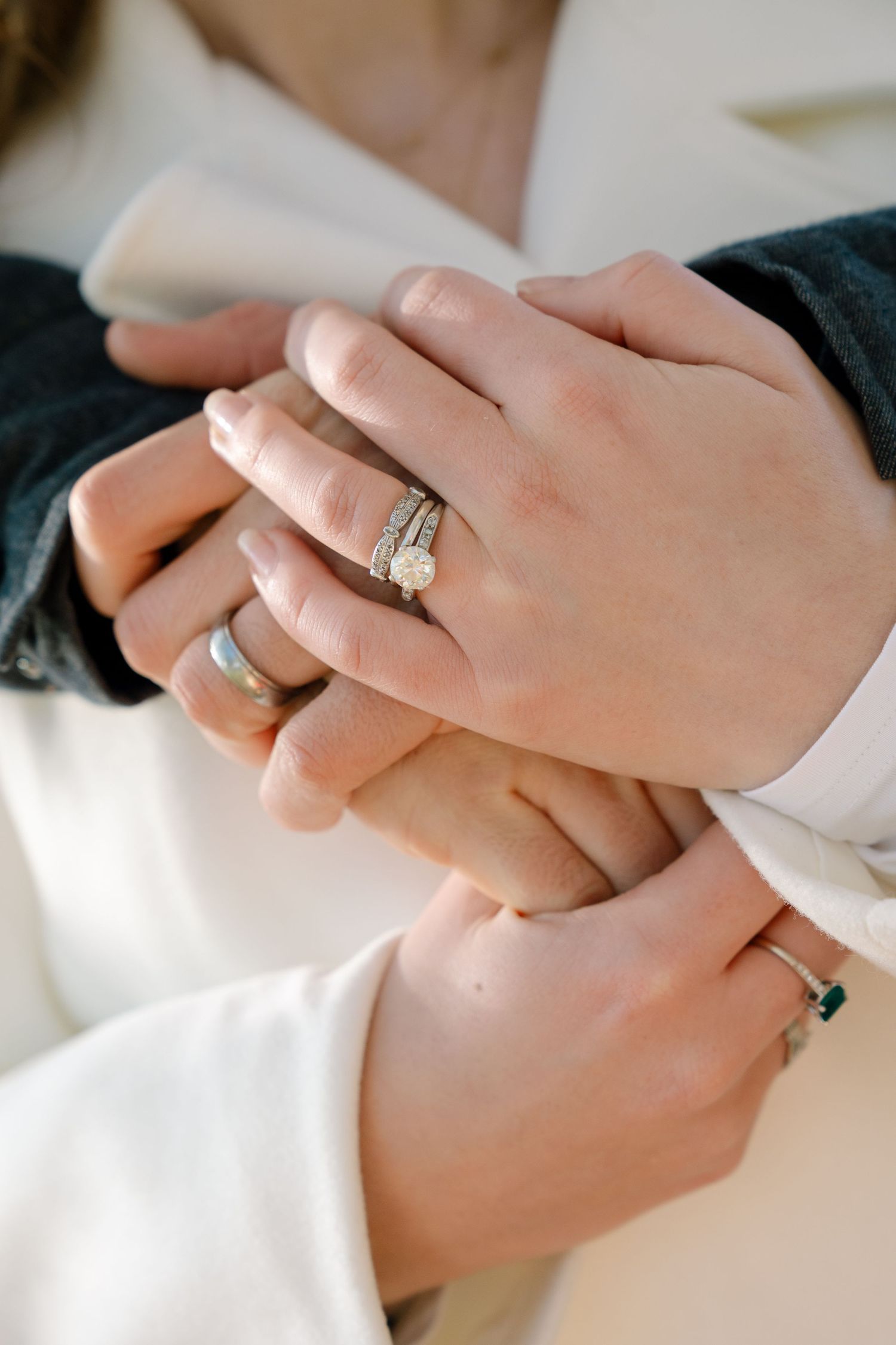 Close up shots of hands wearing engagement rings against a white background.