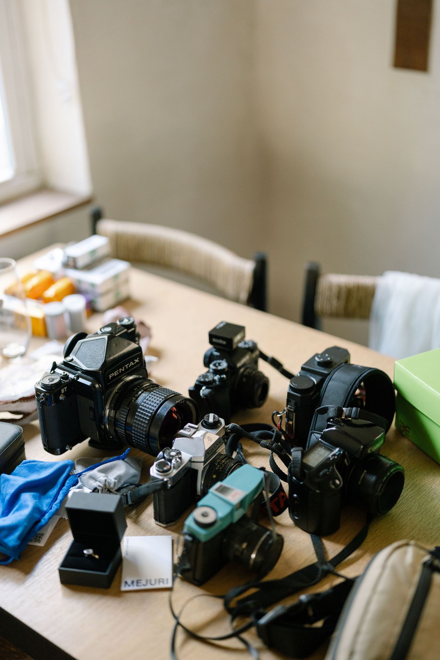 A collection of vintage and modern cameras arranged on a wooden table in natural light.