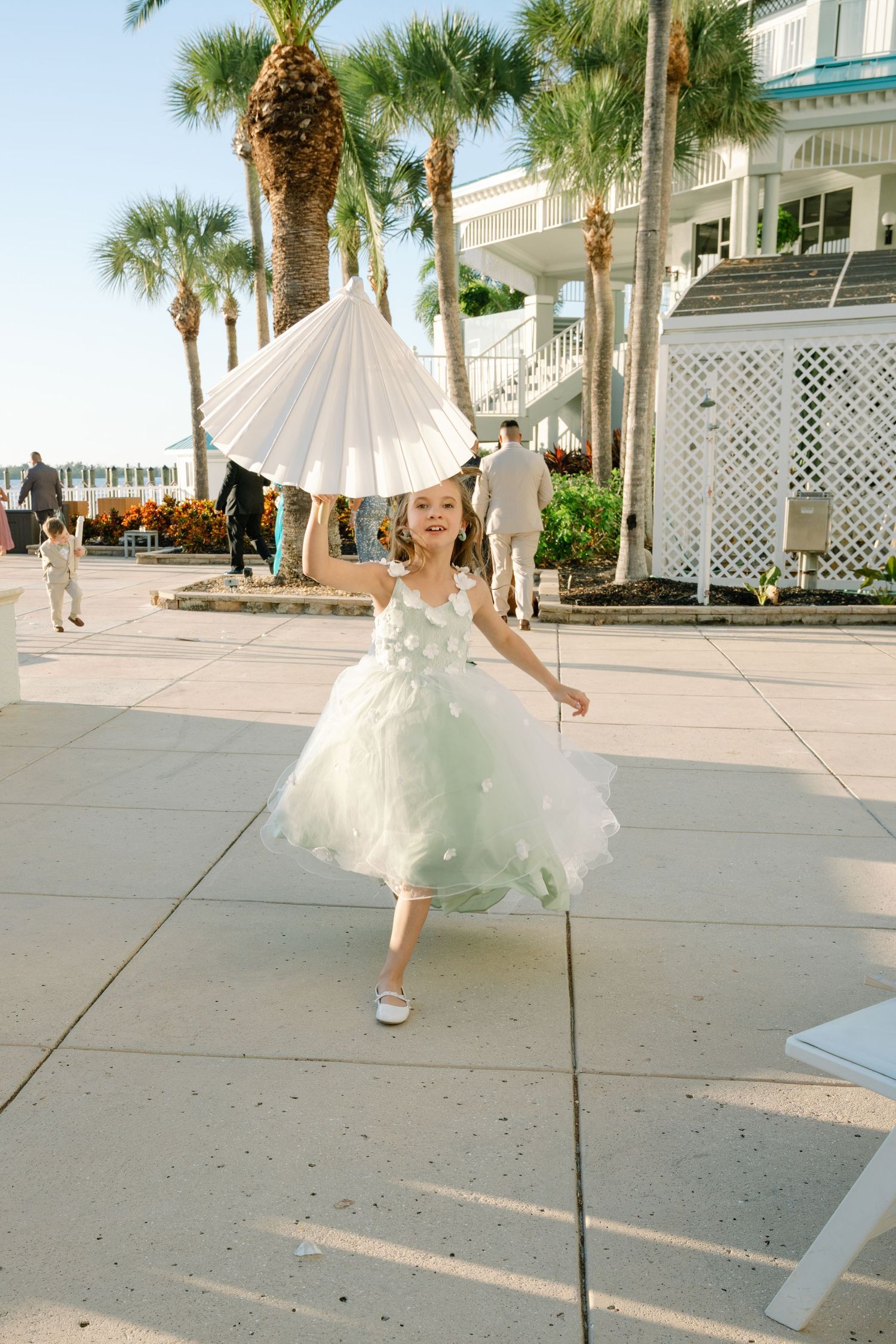 Sequence of a bride twirling in white dress on resort grounds with palm trees.