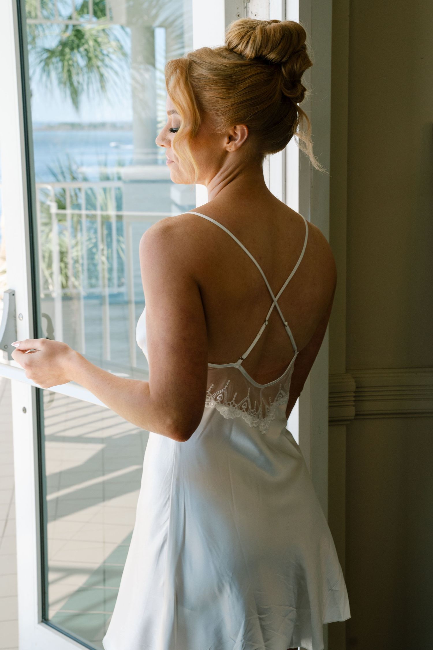 White wedding dress details shown against window with palm trees visible outside.