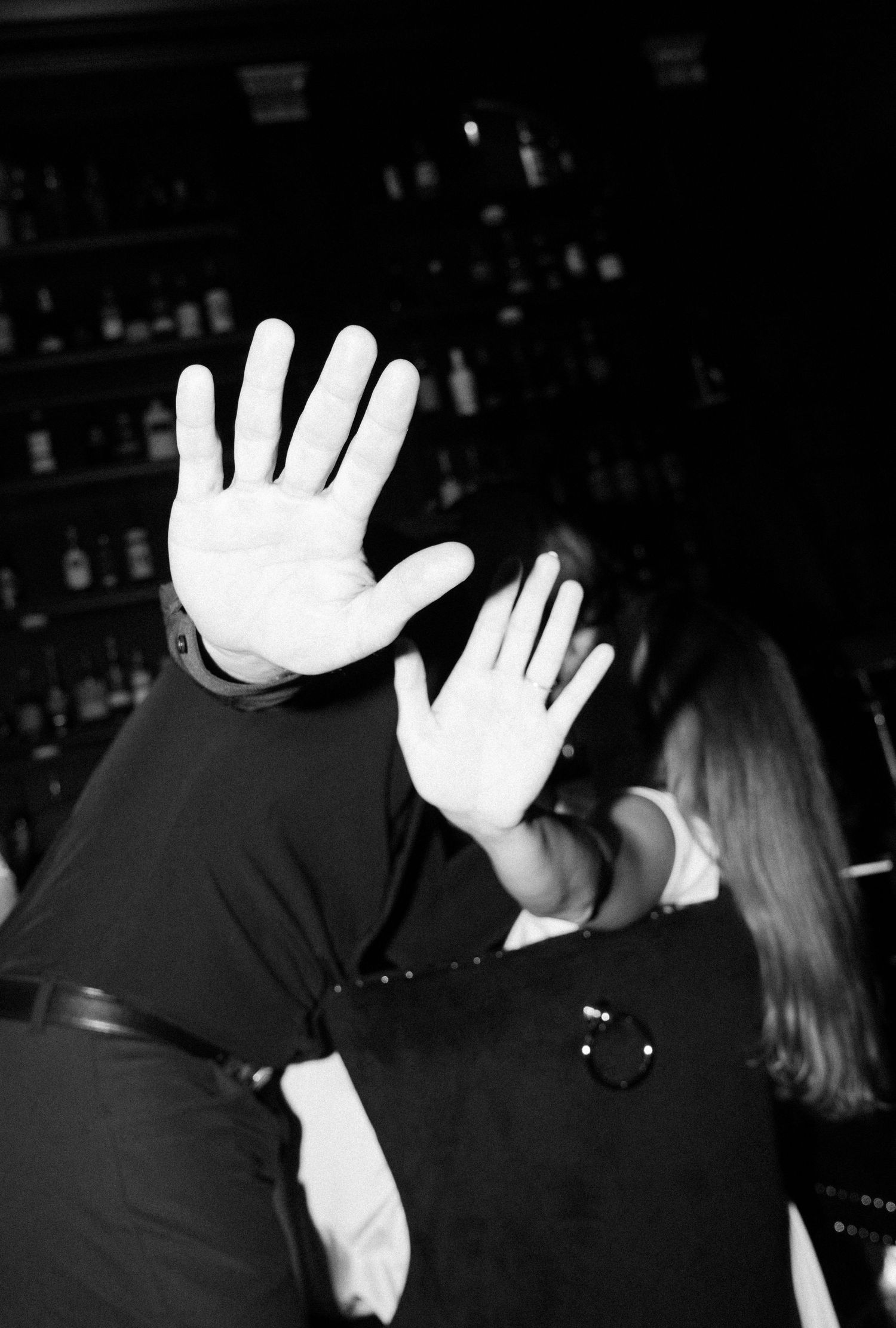 A sequence of black and white photos showing raised hands blocking the camera view in a dark setting.