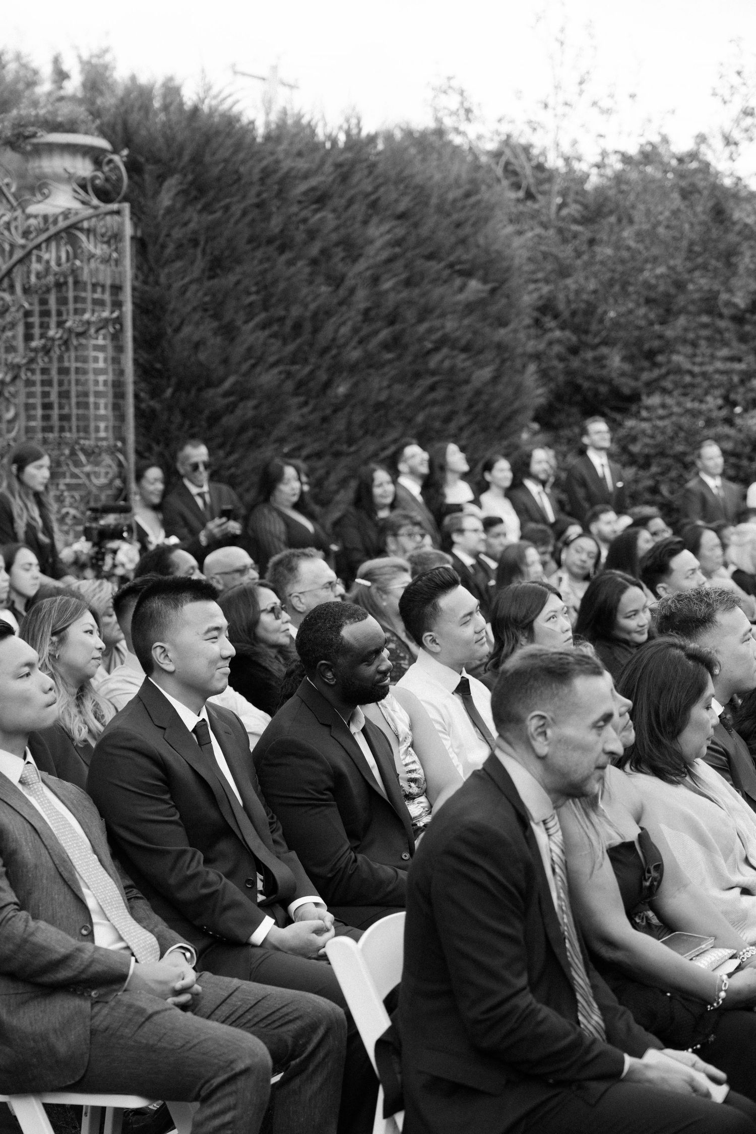 Black and white photo of wedding ceremony guests seated in formal attire.