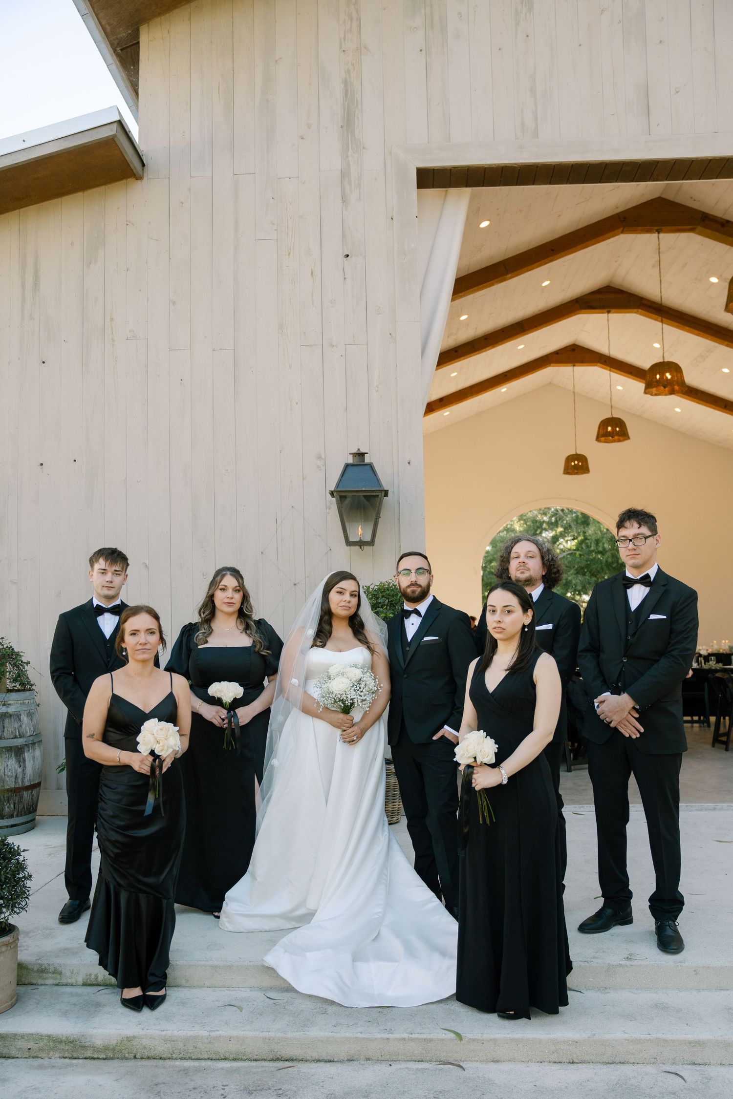 A wedding party posing for a photograph in front of a wooden building.
