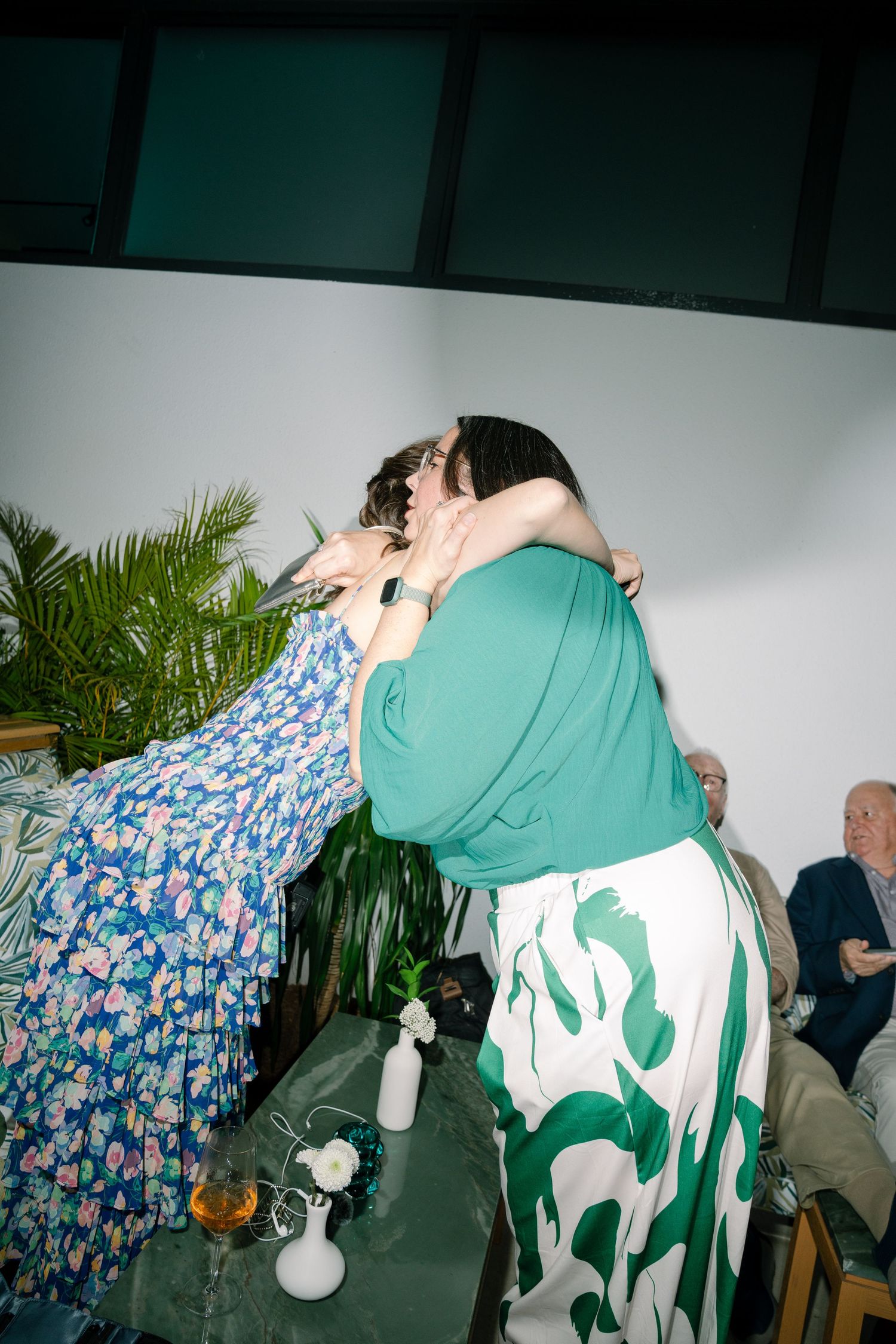People dancing at a party with blue and green patterned clothing visible in the dimly lit space.