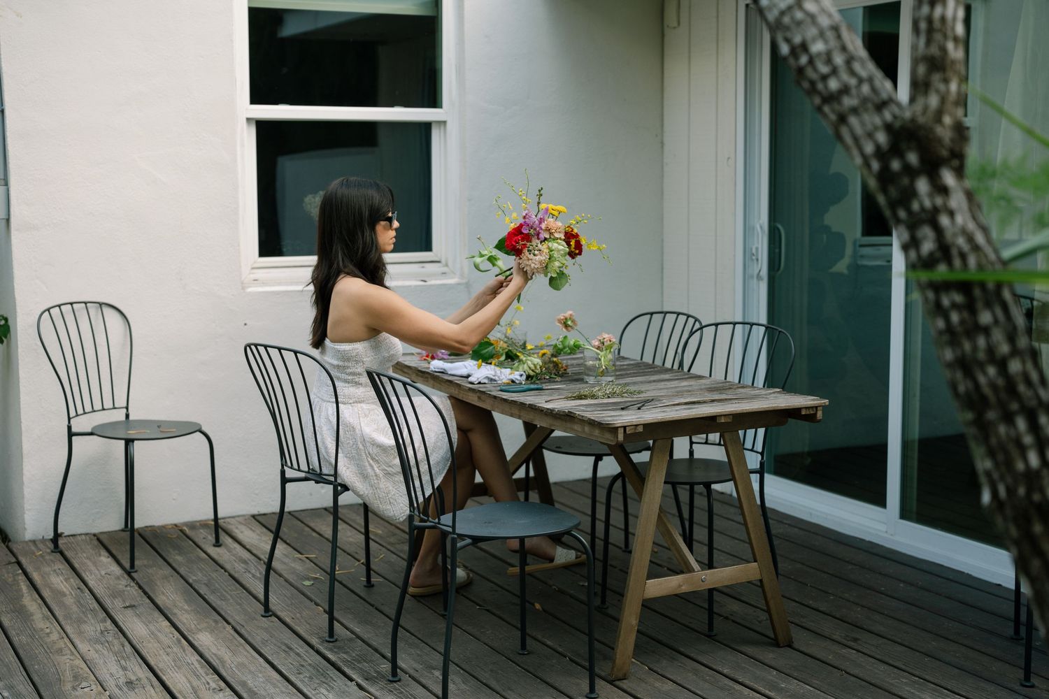Outdoor patio seating area with white chairs and tables arranged on a wooden deck.
