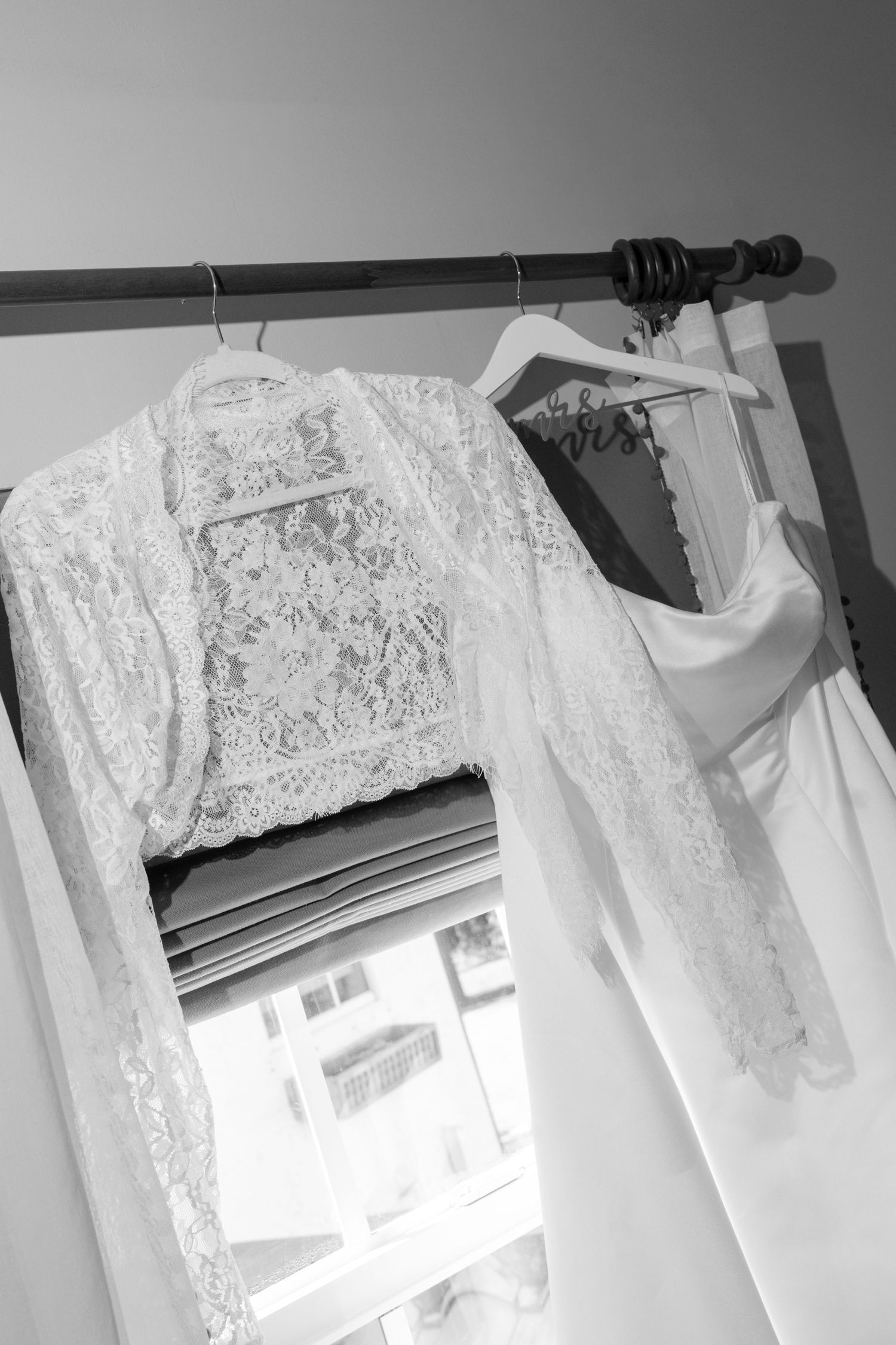 A lace wedding dress hanging on a clothing rack.