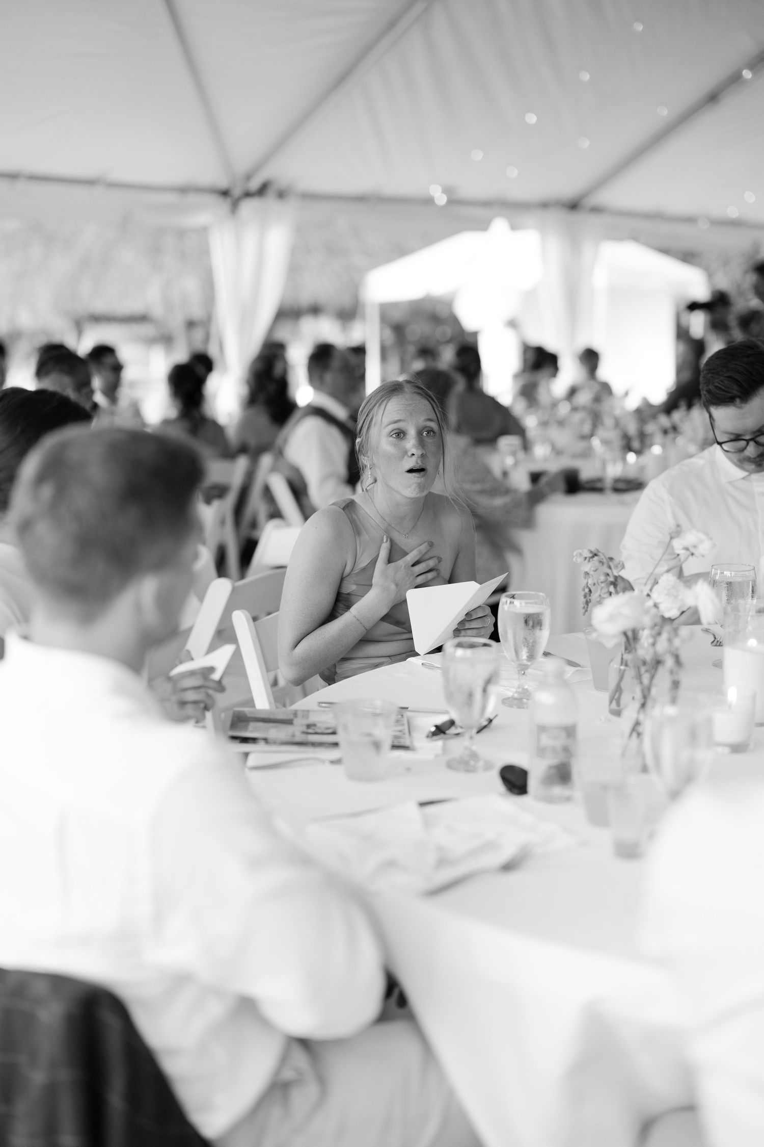 A black and white image of a crowd seated at tables during an event or celebration.