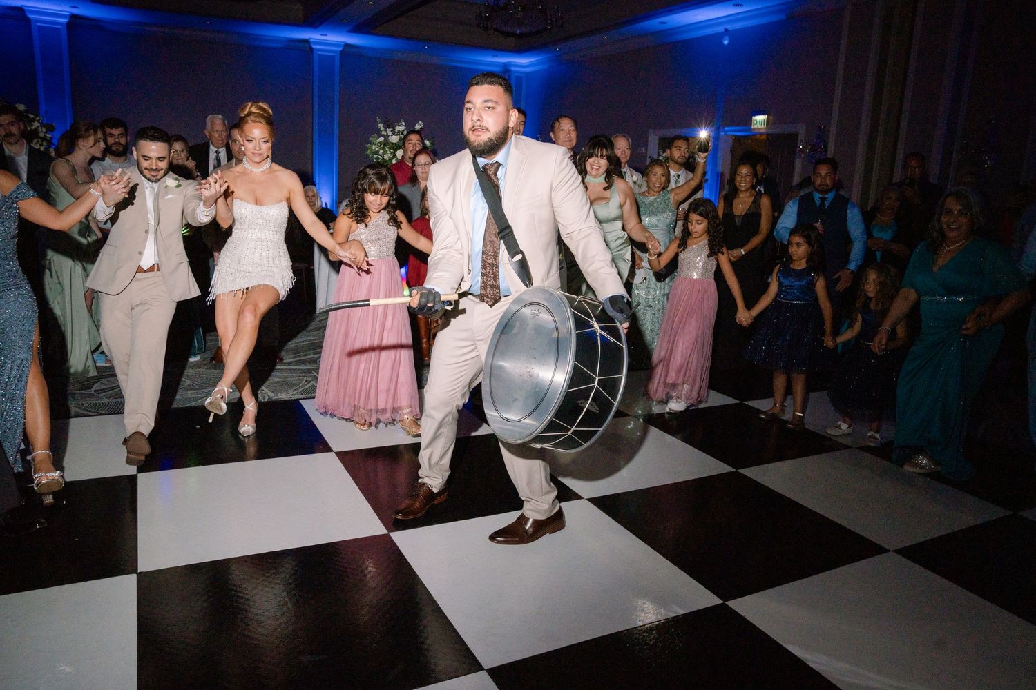 Dance floor scene with blue lighting and guests celebrating at wedding reception.