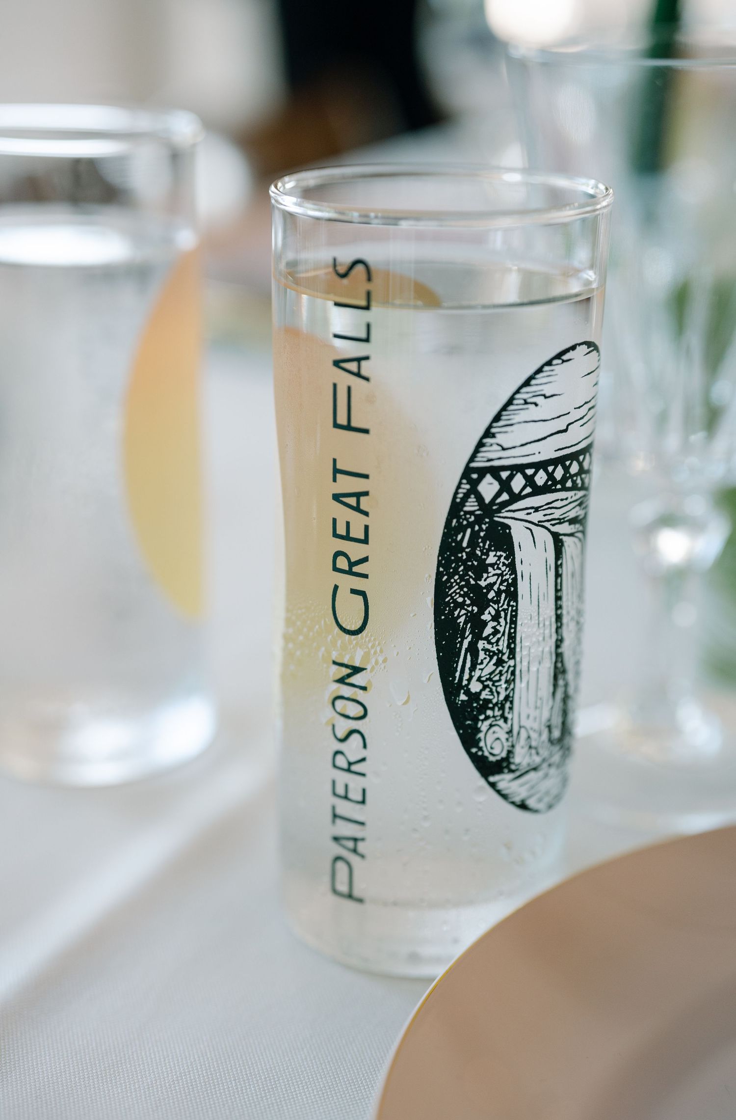 Row of decorative glass cups with artistic designs and text displayed at a formal event.
