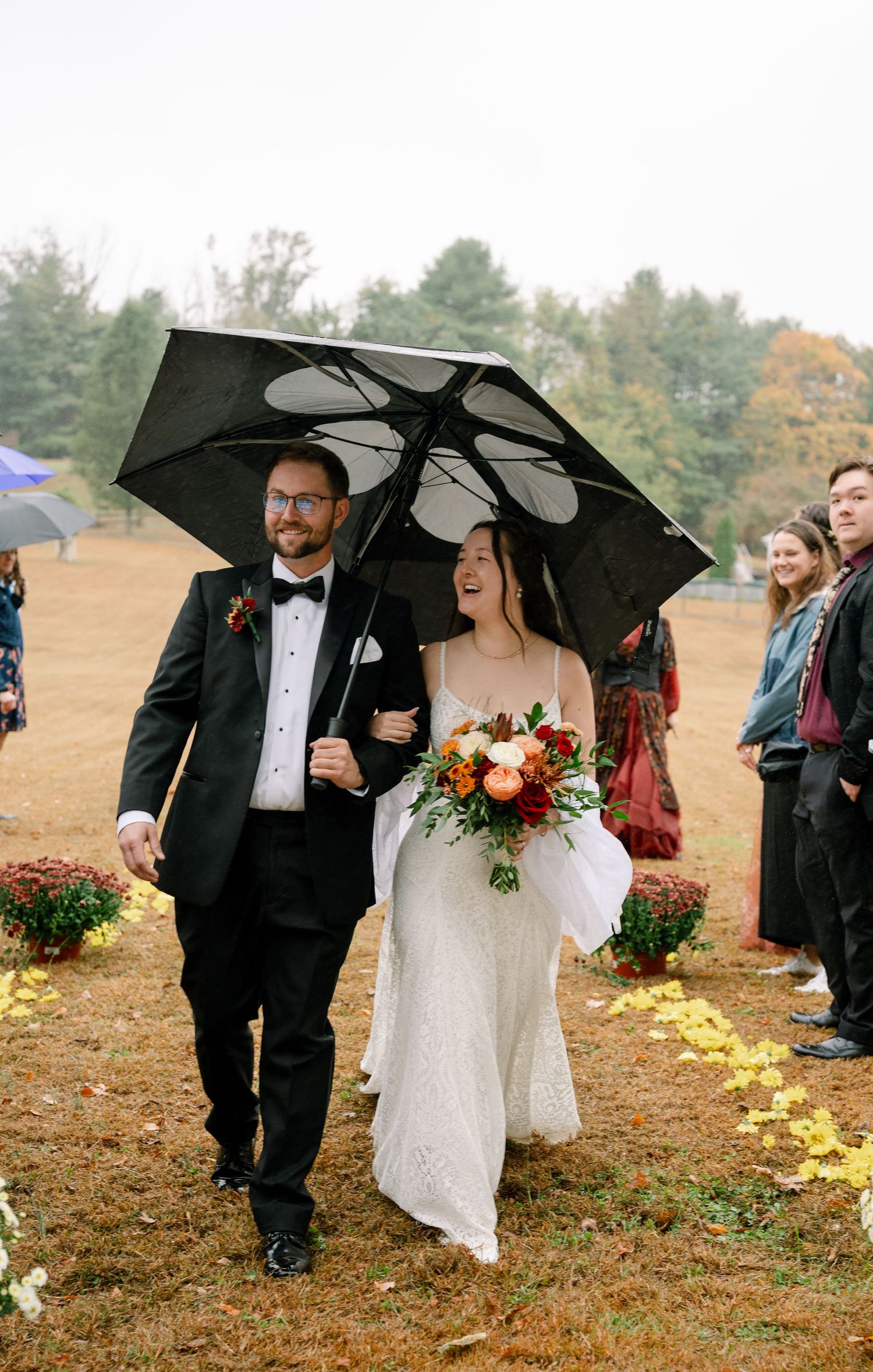 Wedding party walking with black umbrellas on a rainy autumn day.