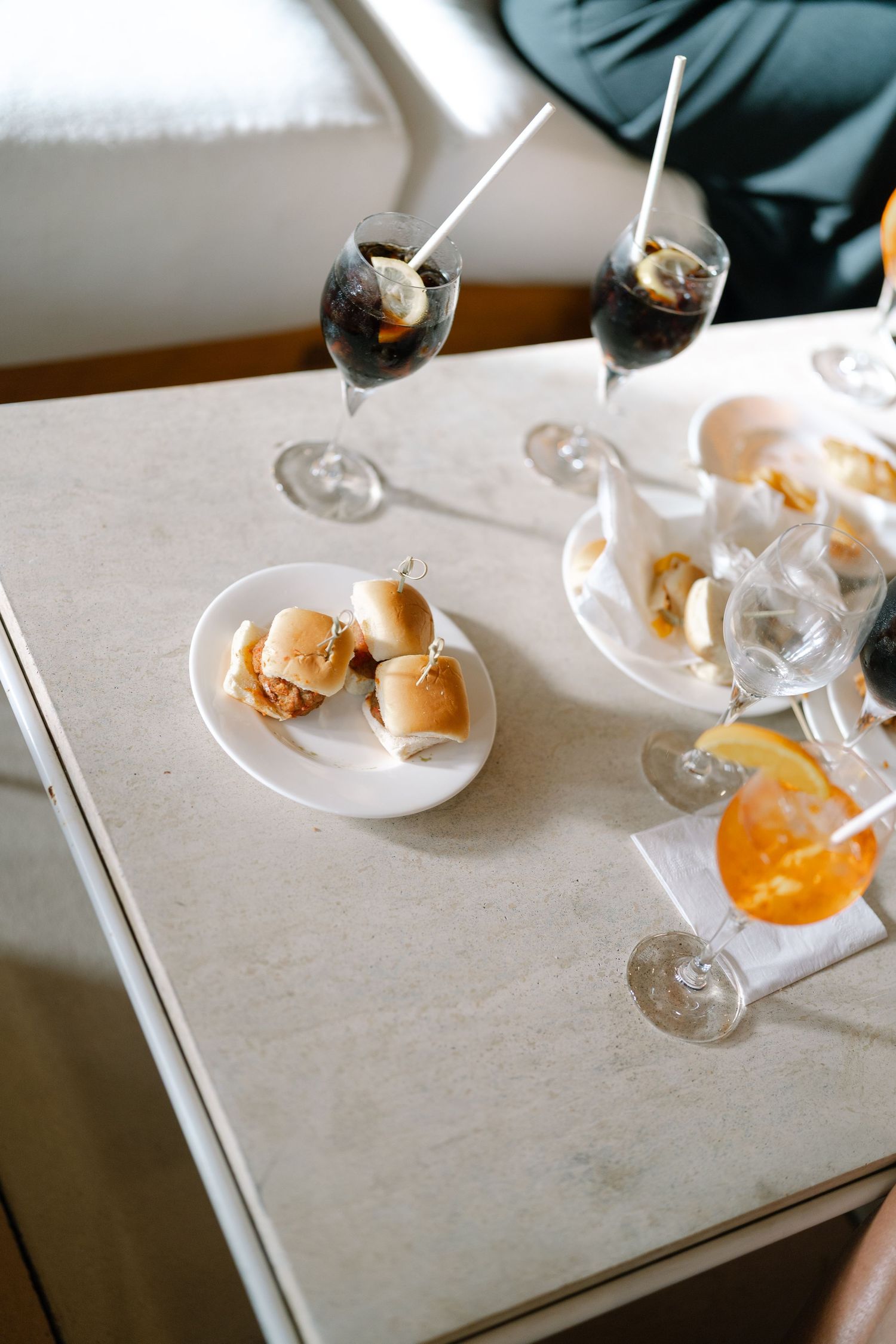 Sequence of orange cocktails and appetizers being served on white plates.