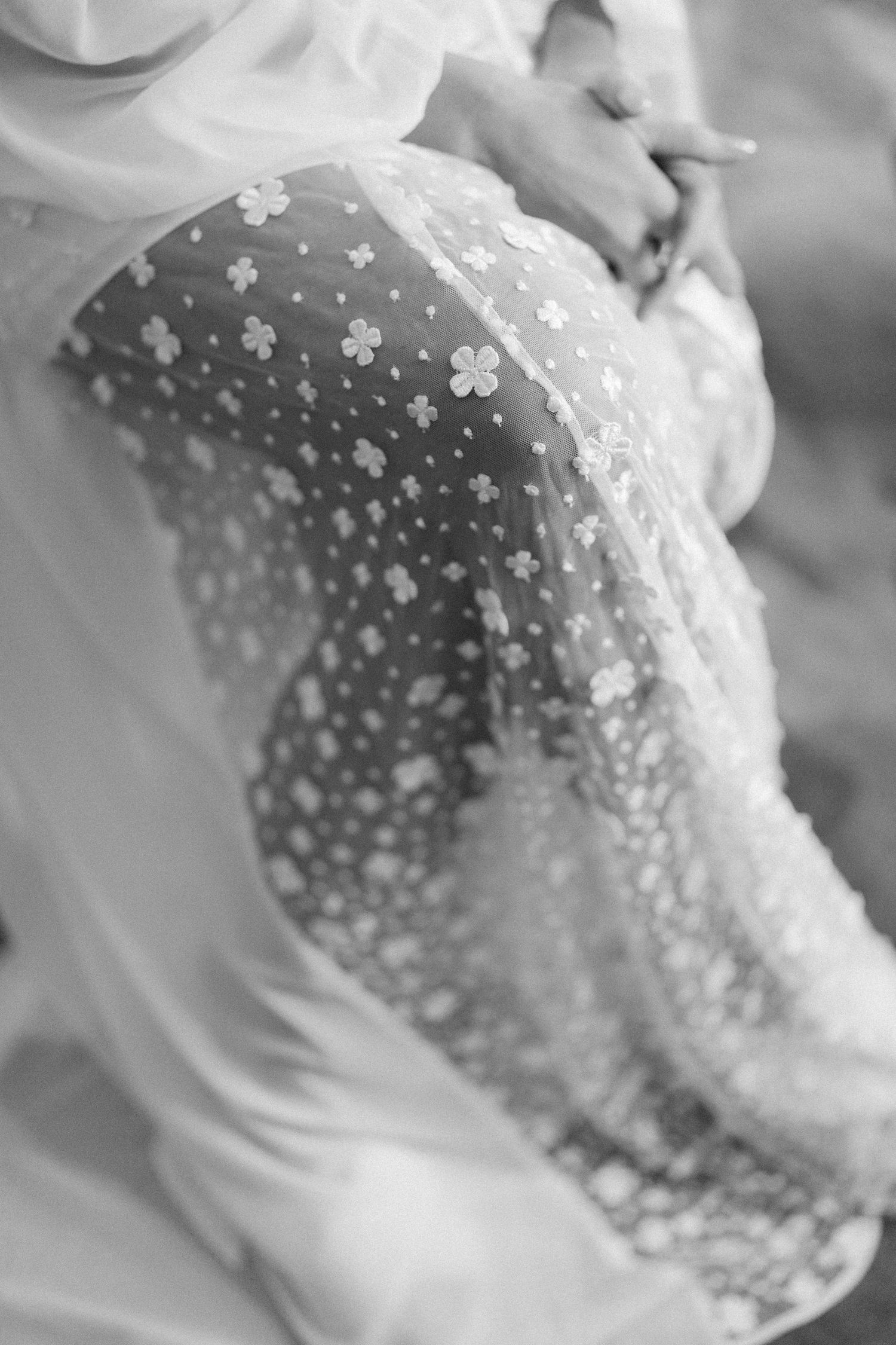 Close-up detail of delicate pearl beading on white wedding dress fabric.