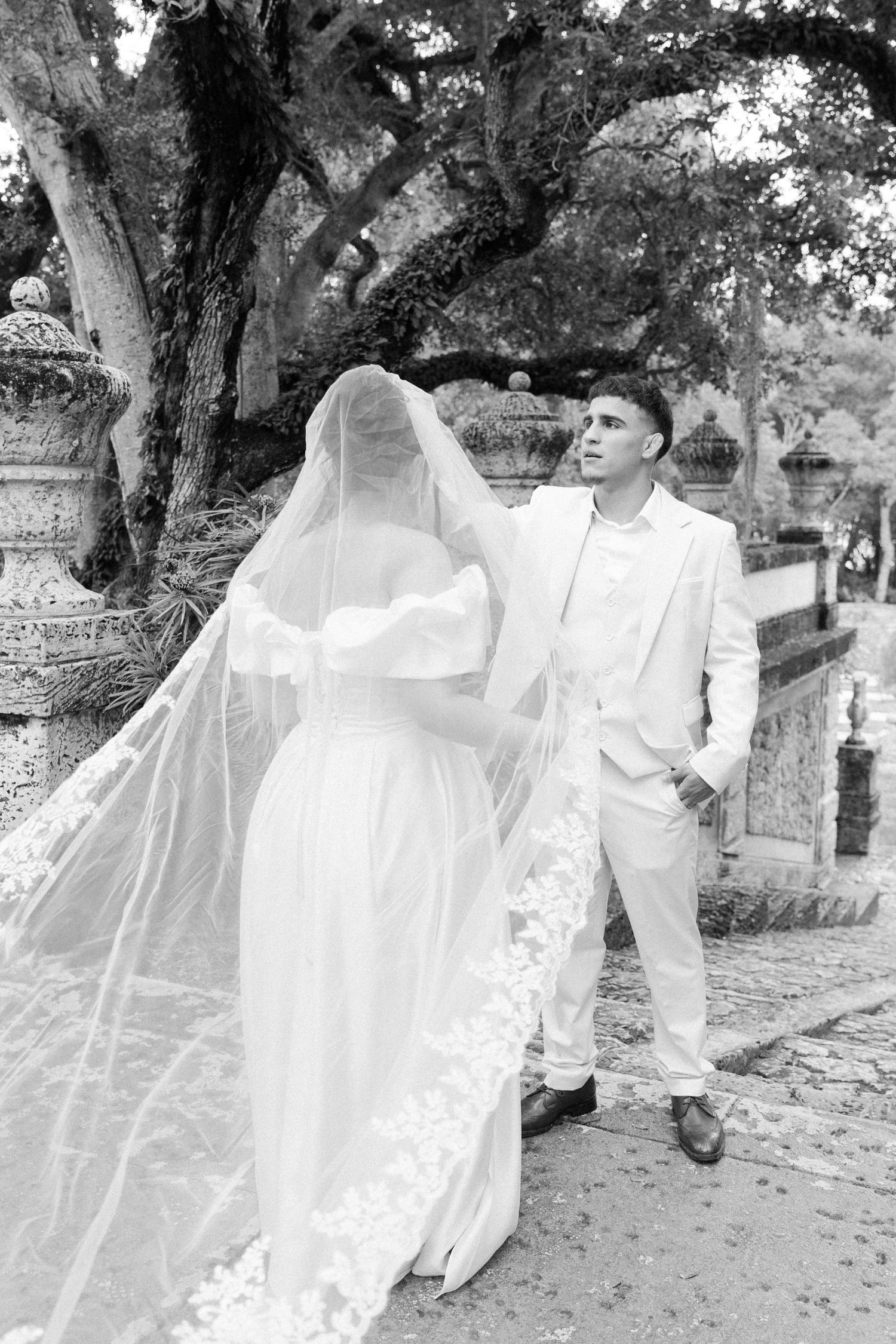 Black and white photos of a bride and groom walking and posing together outdoors among trees.