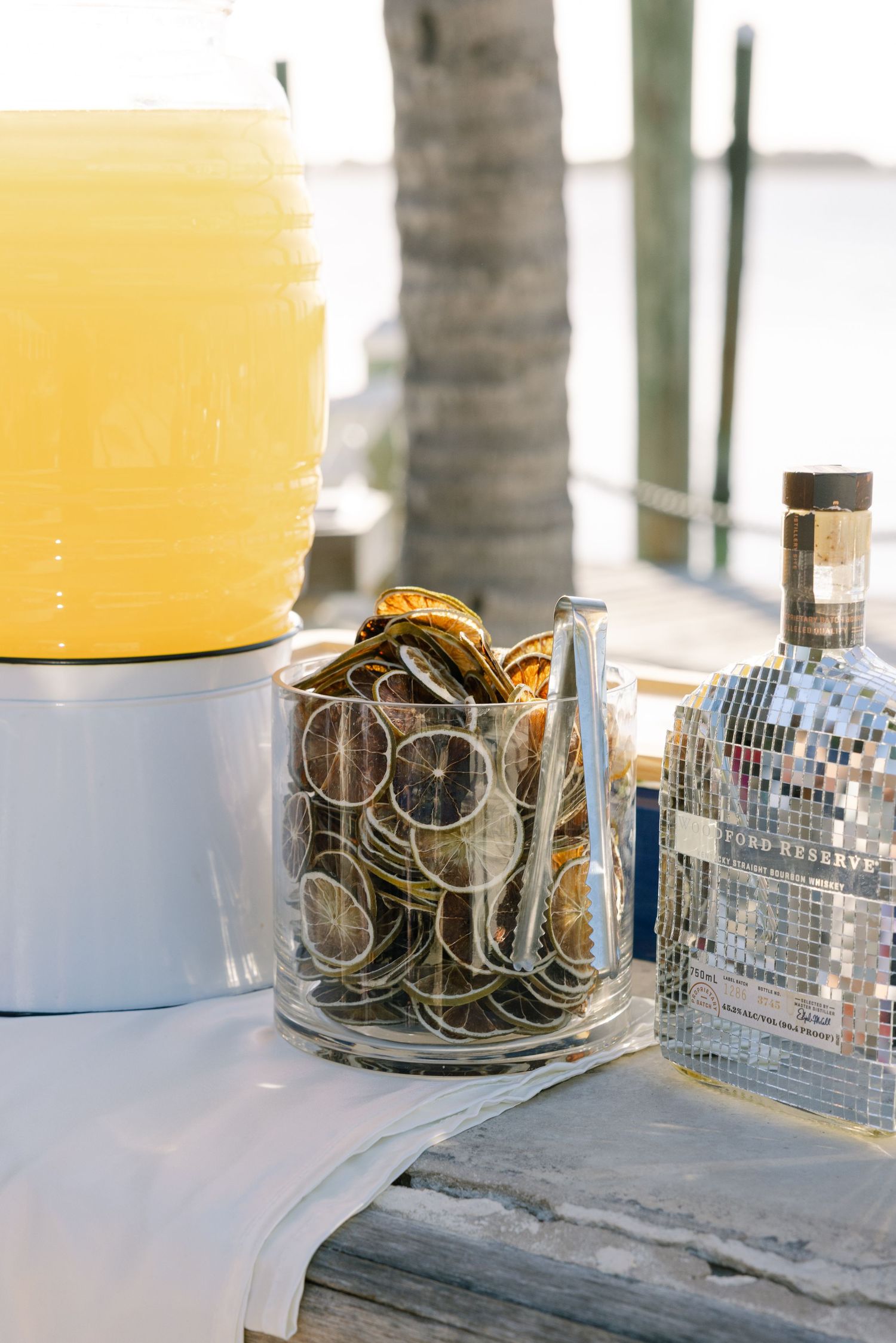 A glass jar filled with dried citrus slices and other decorative elements on a table with a yellow container.