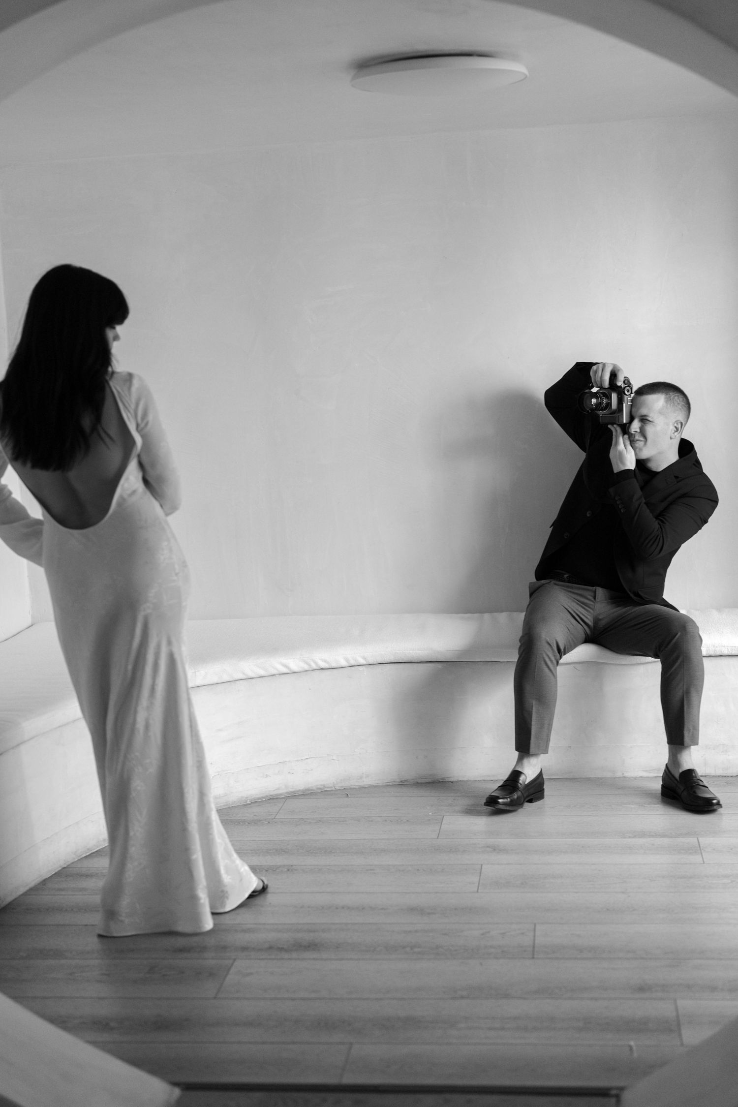 Artistic black and white photograph of people in minimalist white room setting.