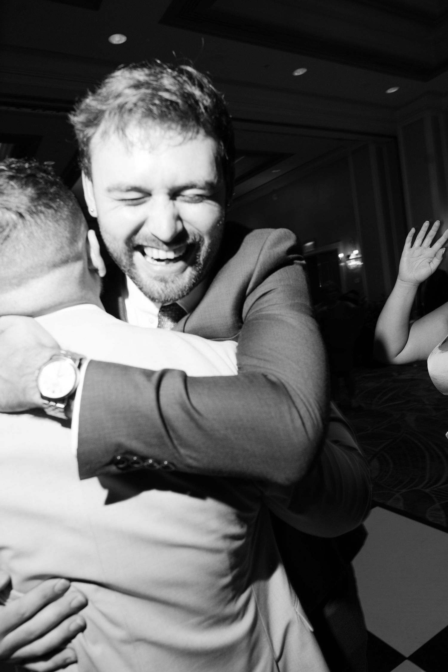 Black and white photos capturing emotional embraces between people at a celebration.