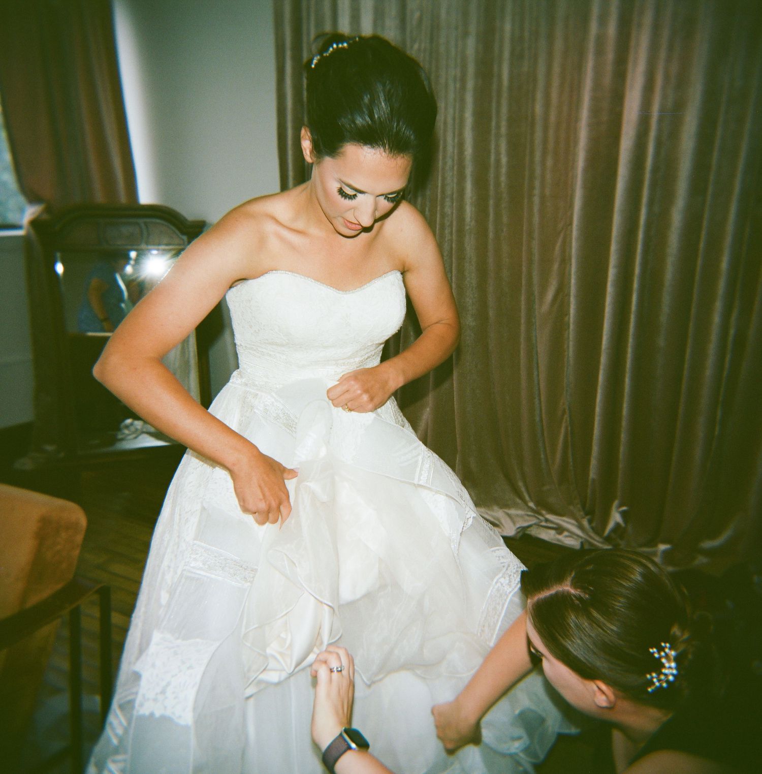 Close up of a white lace wedding dress being adjusted and fitted.