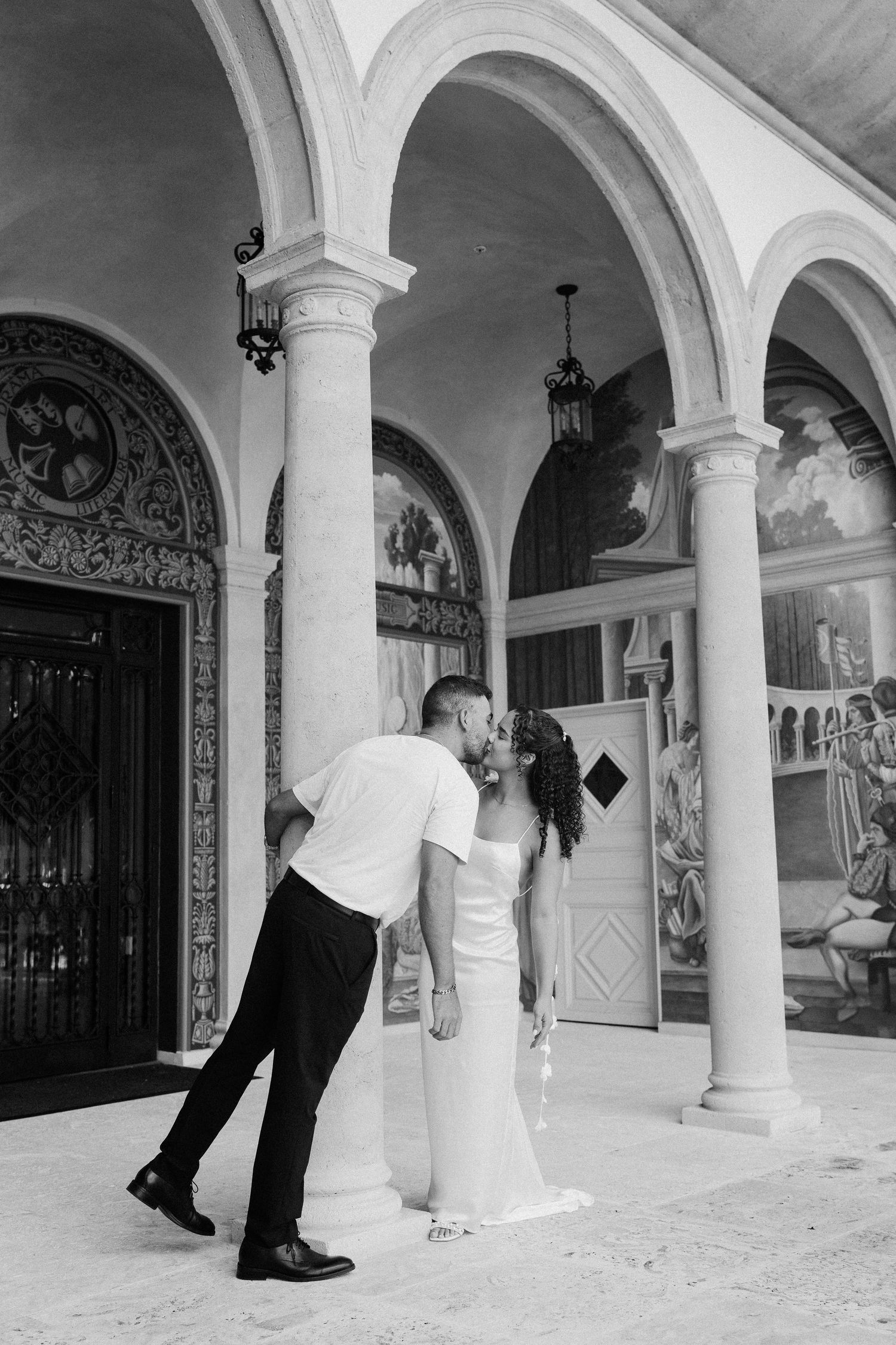 A black and white photo sequence shows a playful scene of figures peeking around elegant white columns in an arched hallway.