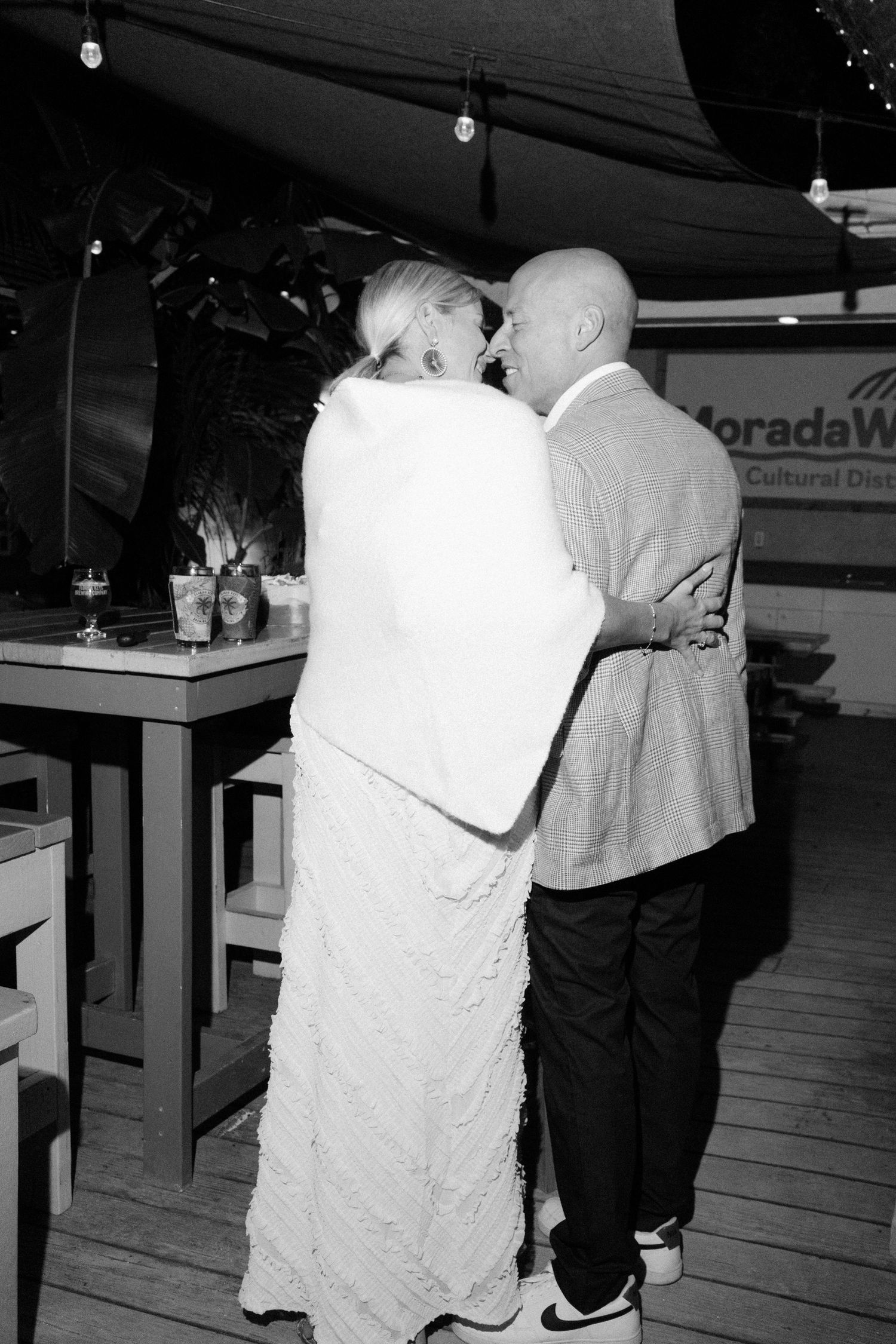 Black and white photo of people dancing together on a wooden deck.