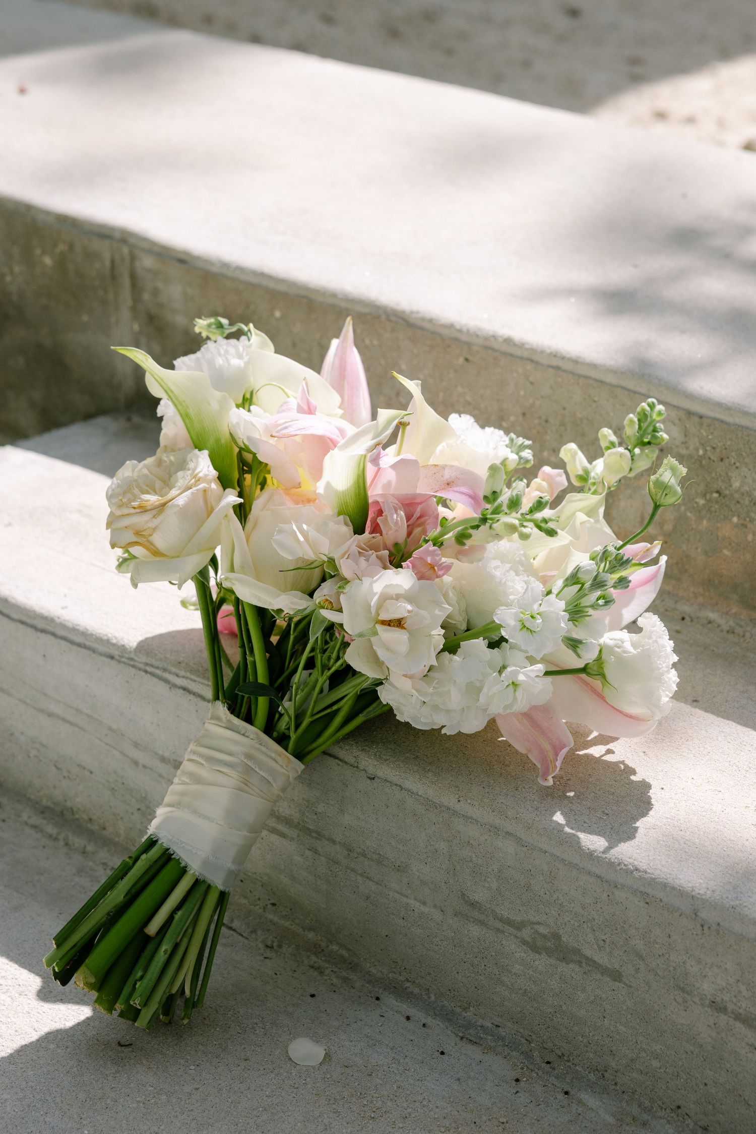 A bouquet of white and pink flowers on a concrete surface.