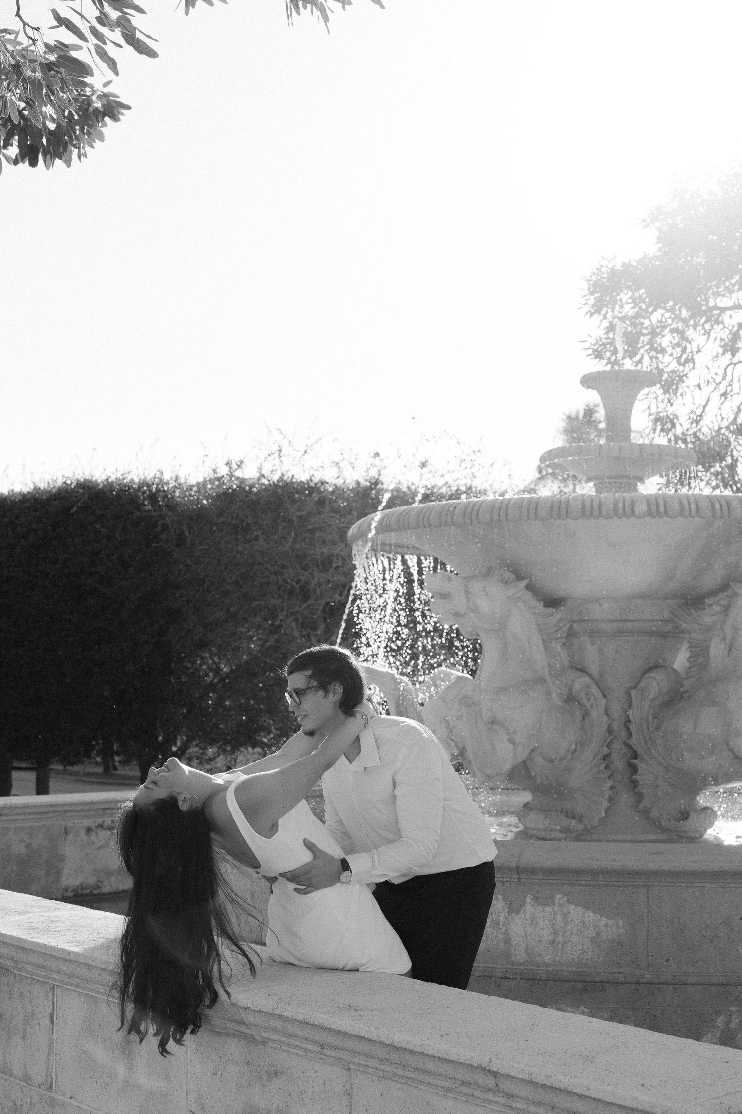 A romantic couple shares an intimate dance dip pose against a stone architectural backdrop.