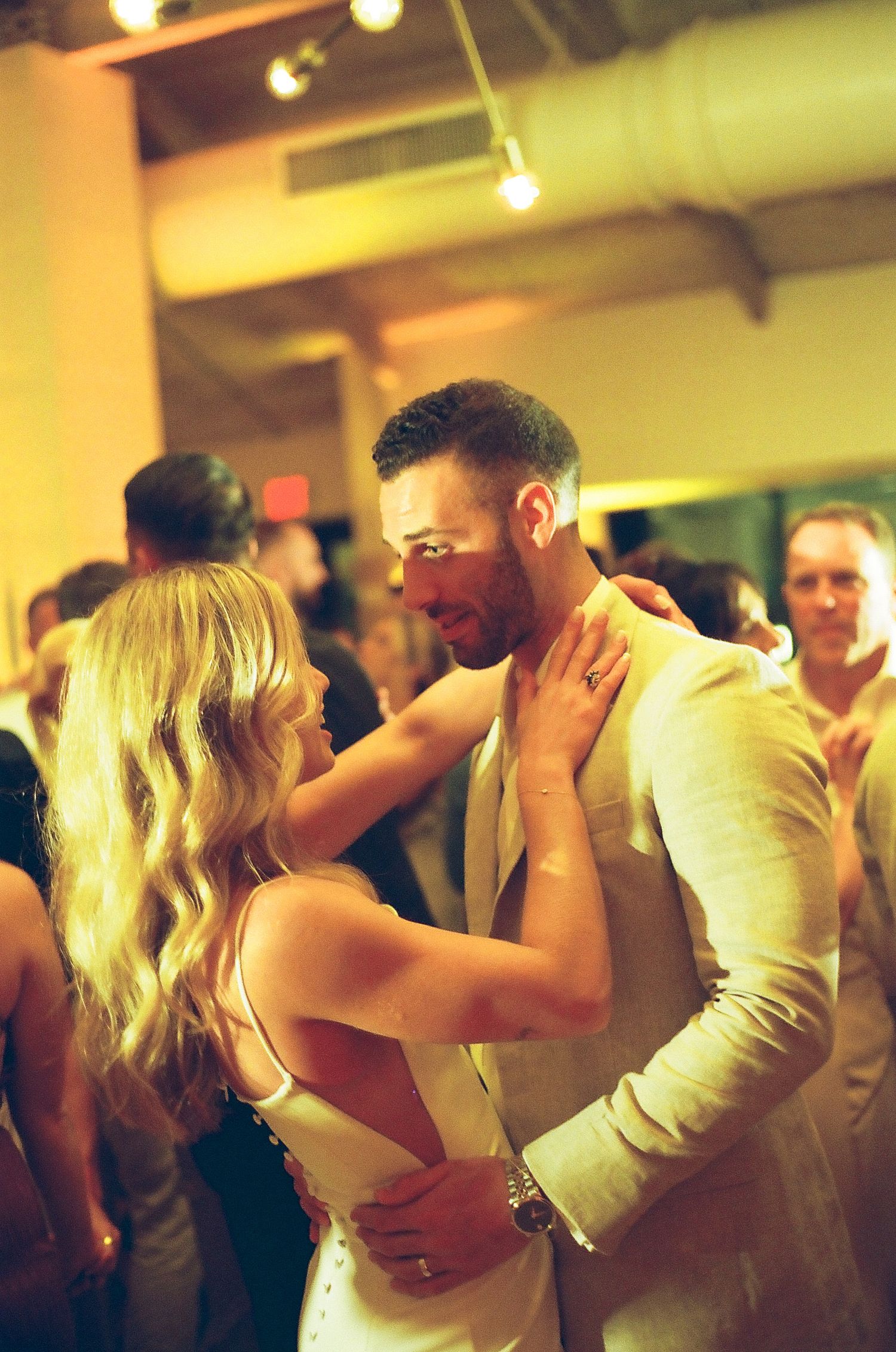 Intimate dance moment captured in warm lighting at wedding reception.