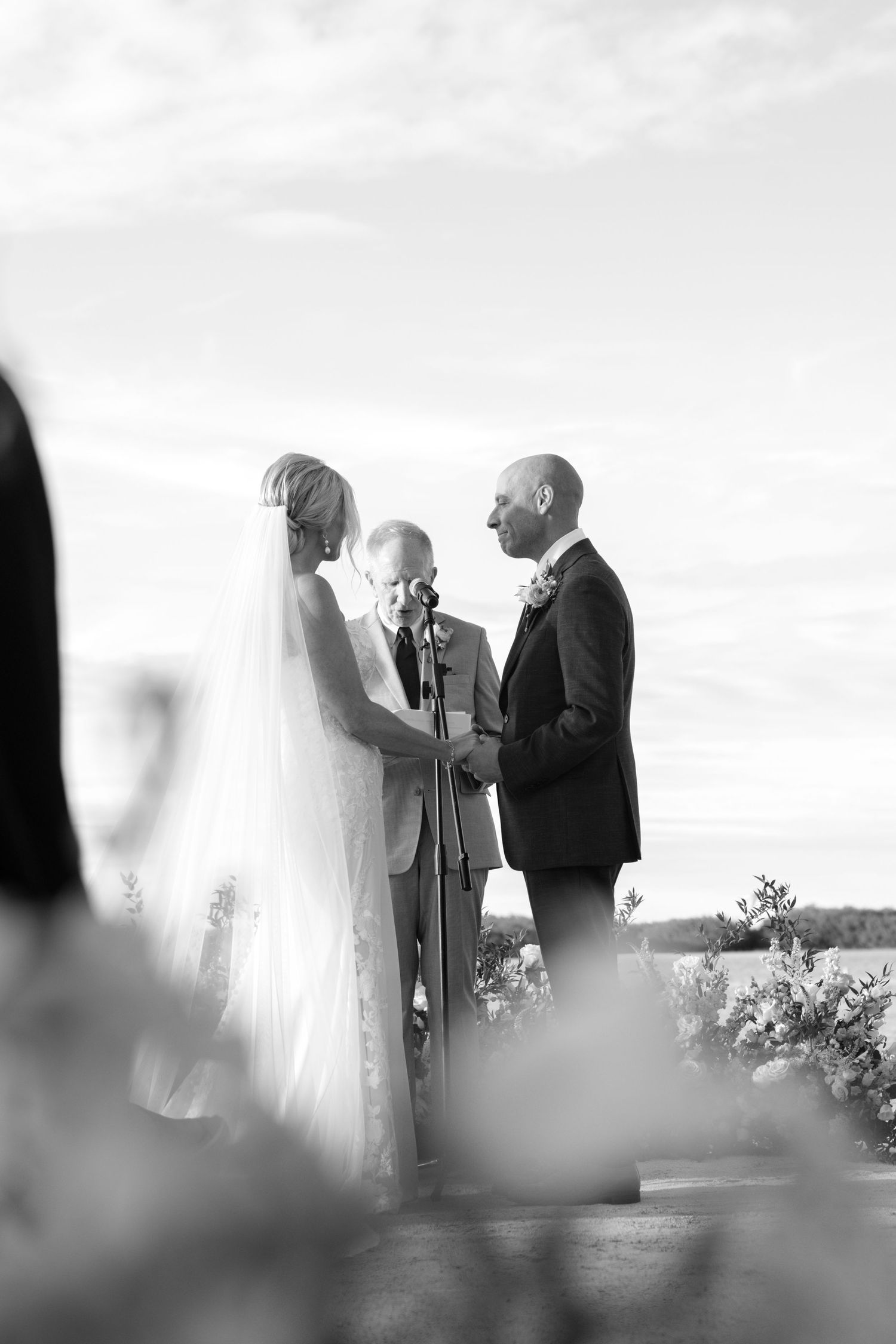 An intimate outdoor wedding ceremony taking place against a waterfront backdrop.