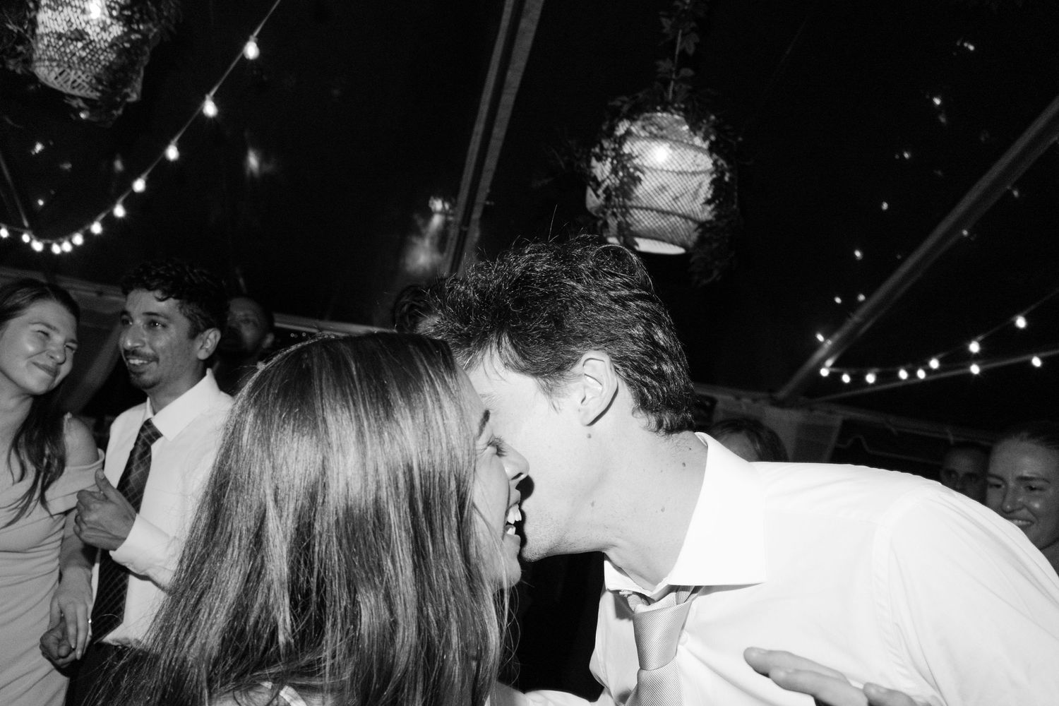 Black and white photo of couple sharing a kiss on the dance floor at a wedding reception.
