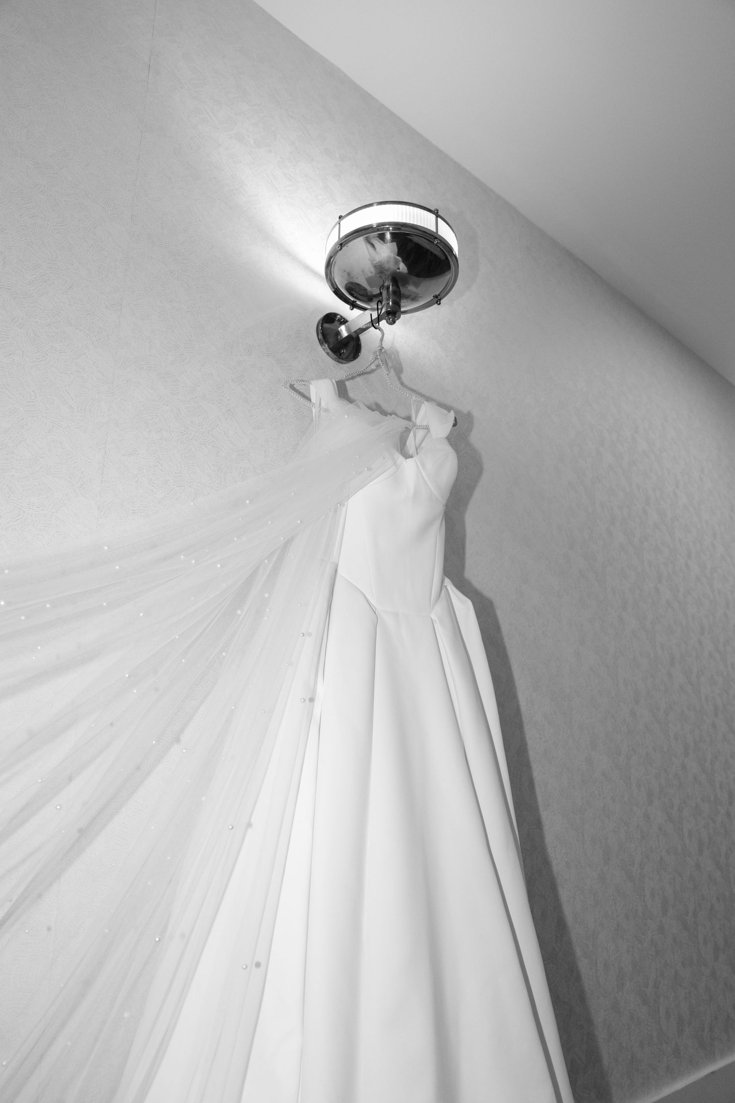 White sheer curtain or fabric canopy dramatically draped from a ceiling light fixture in monochrome.