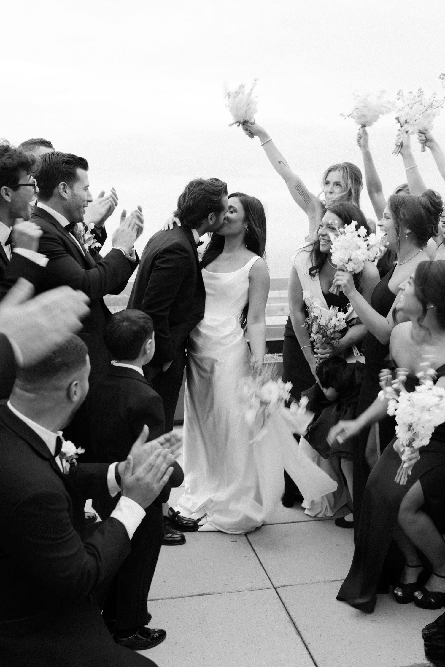 Wedding celebration with guests dancing and celebrating in black and white photography.
