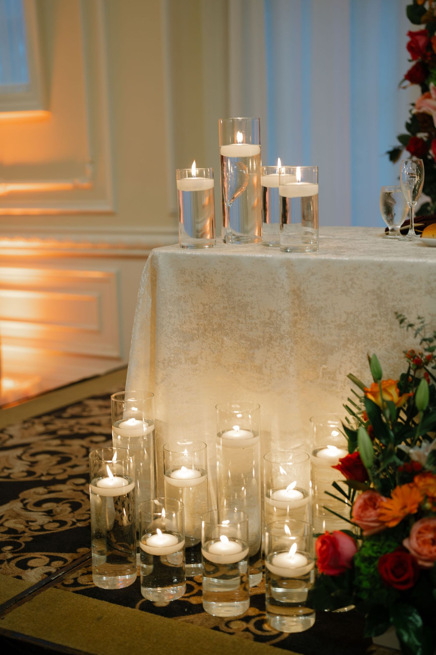 Romantic candlelit wedding decor with floating candles in glass cylinders.