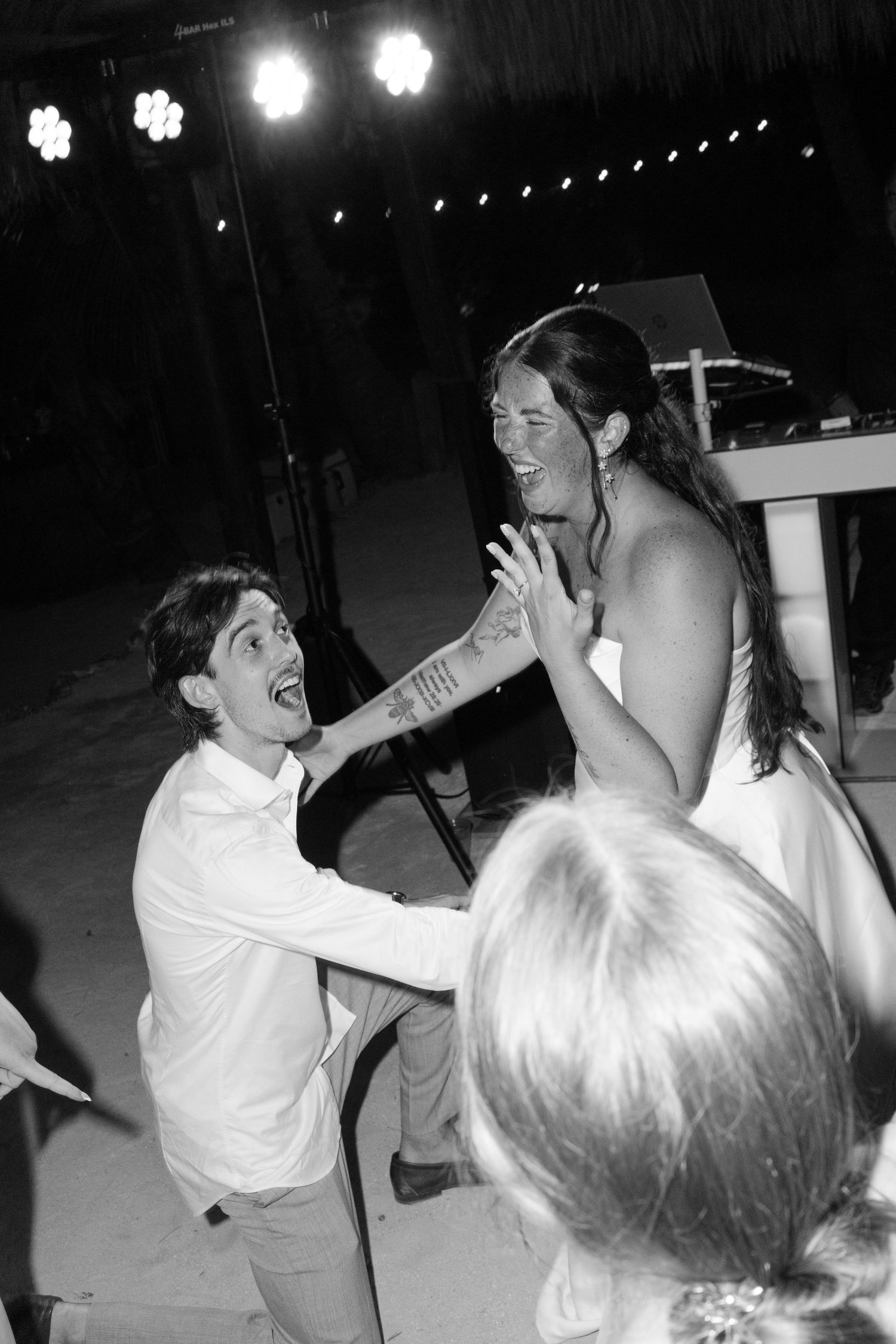 Two people, a man and a woman, interacting and smiling at each other on a stage with bright lights.