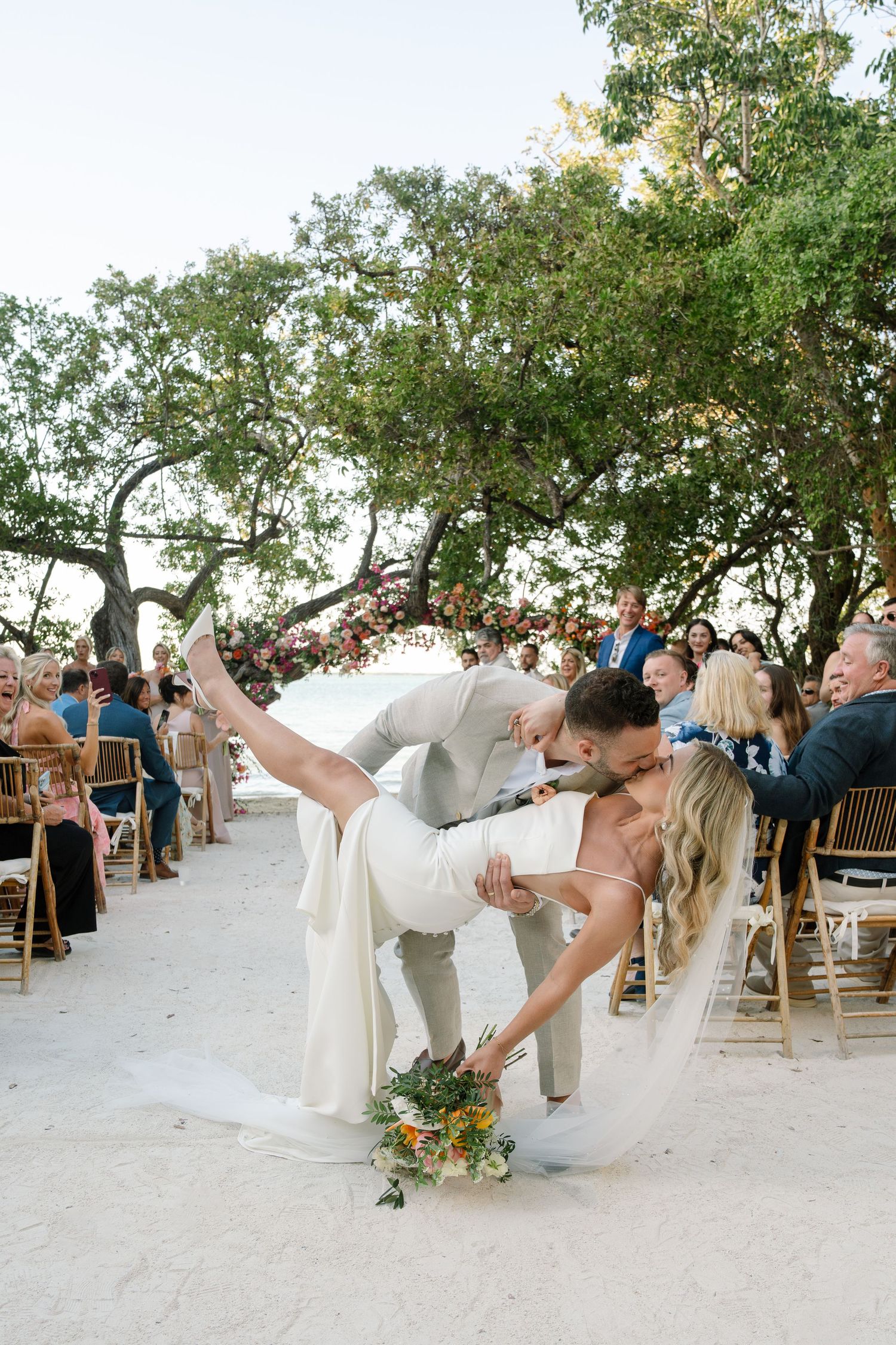 Wedding couple performing romantic dips during their beach celebration.