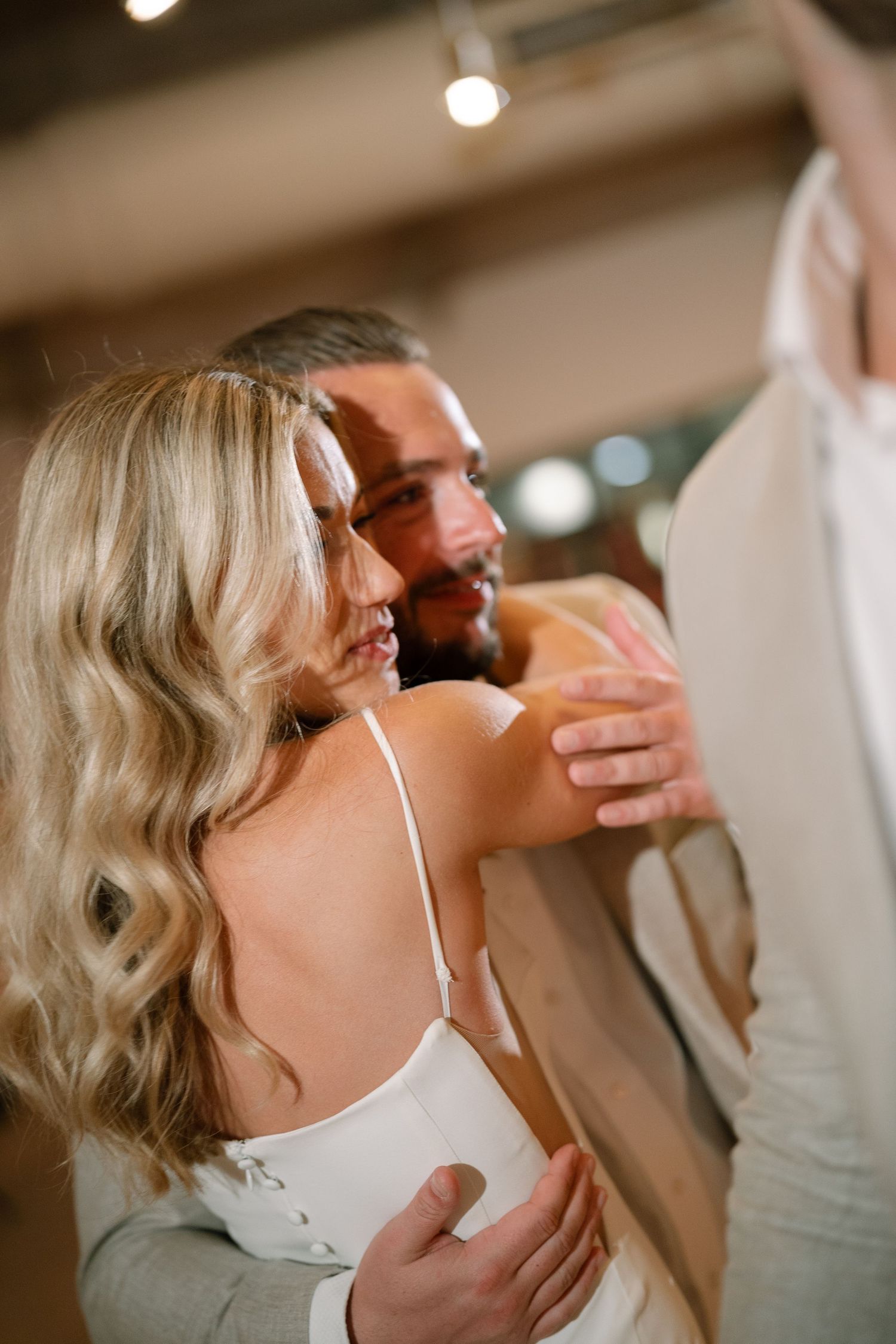 An intimate candid moment captured during a wedding reception with warm indoor lighting.