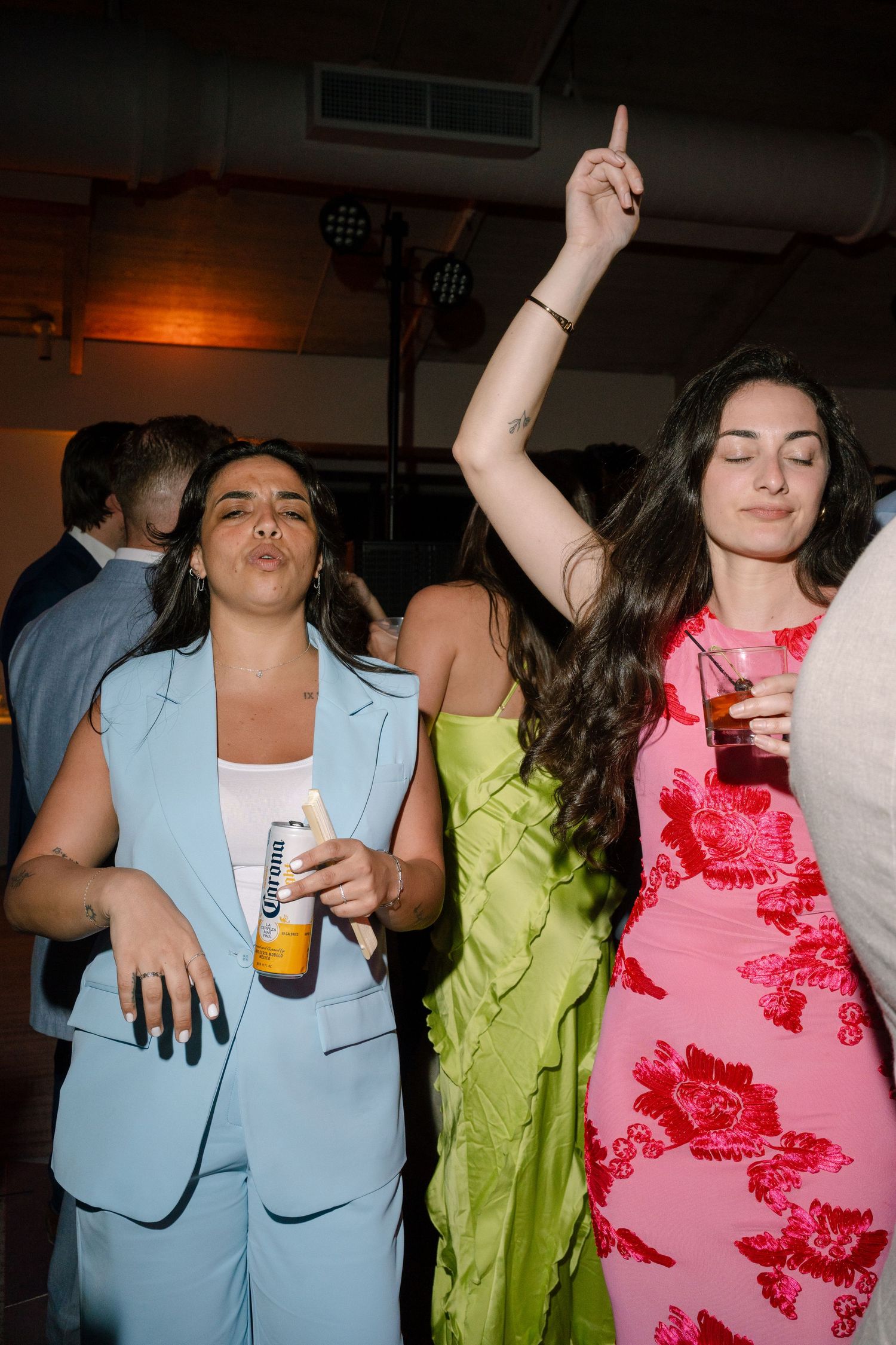 Party guests dancing and enjoying drinks at a lively wedding reception.