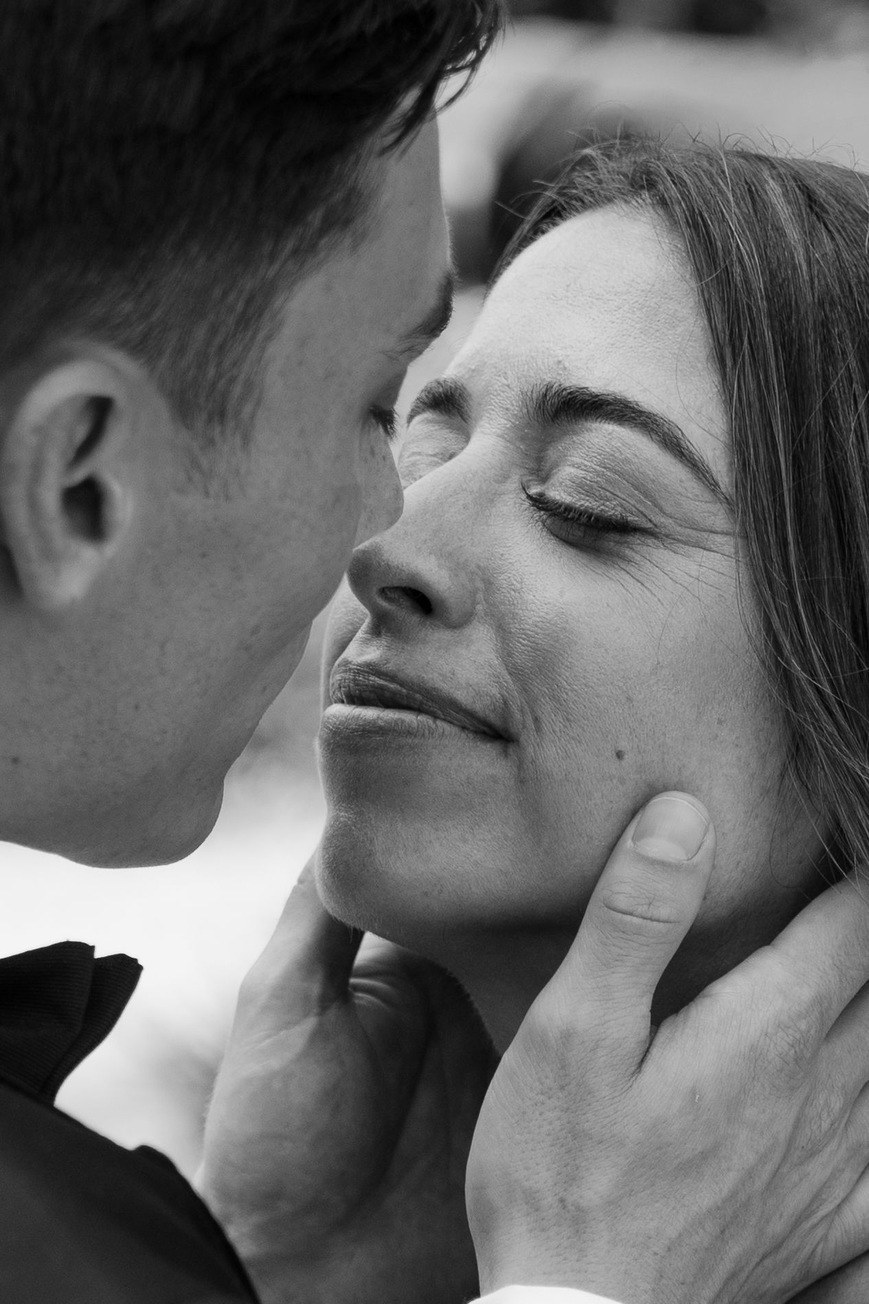 Intimate black and white close-up of groom tenderly cupping brides face as they share a romantic moment.