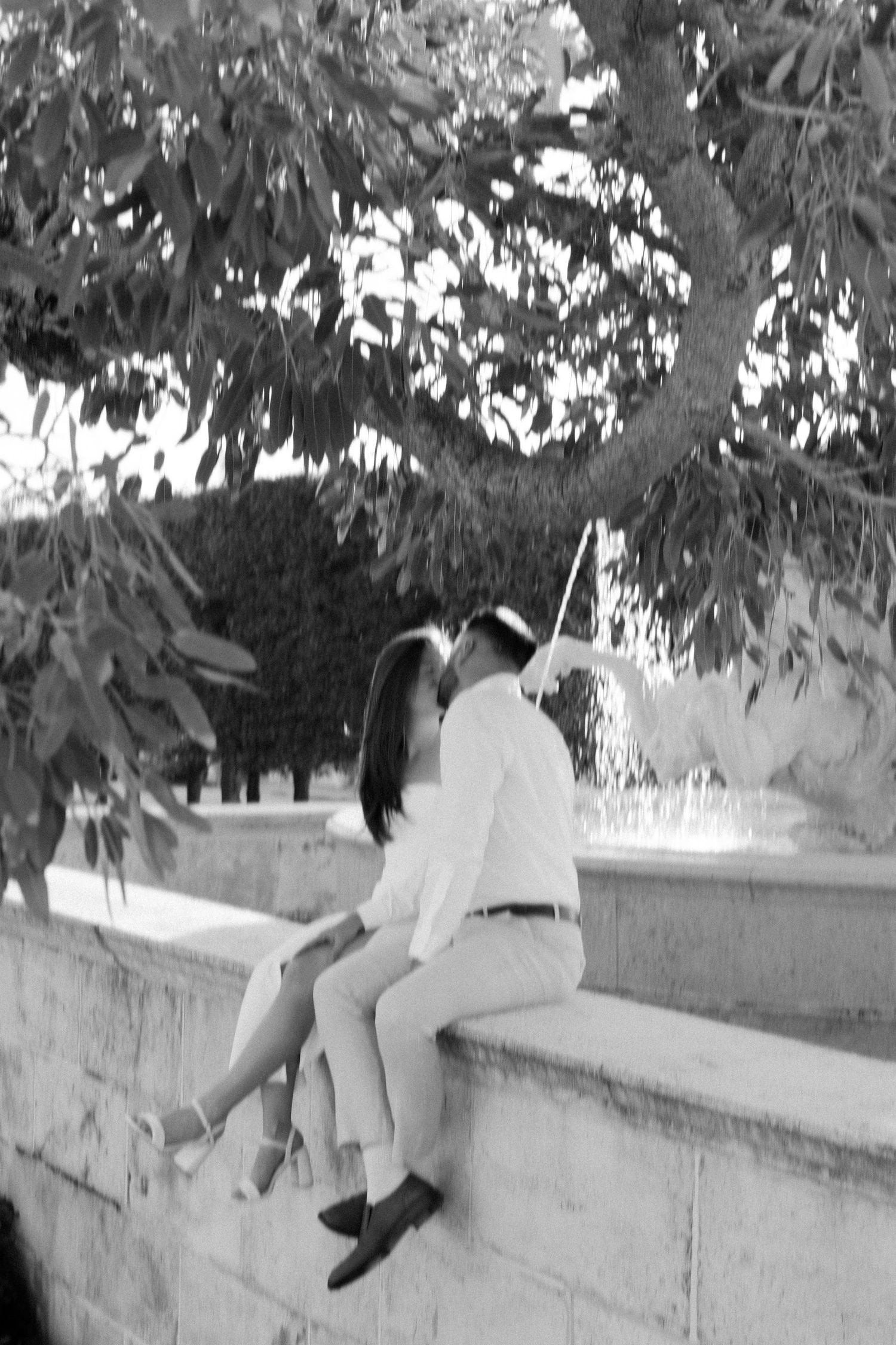 A sequence of black and white photos shows a person sitting on a low wall with trees in the background.