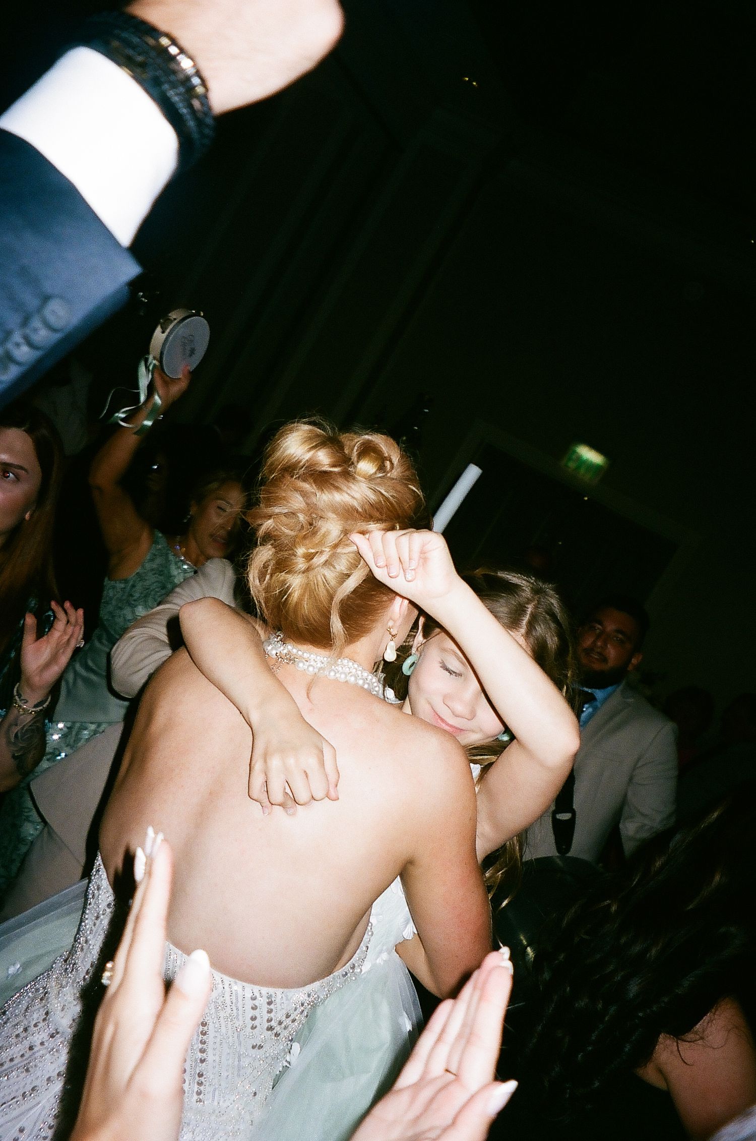 Dancing and celebrating at a dimly lit wedding reception with disco ball reflections in the background.