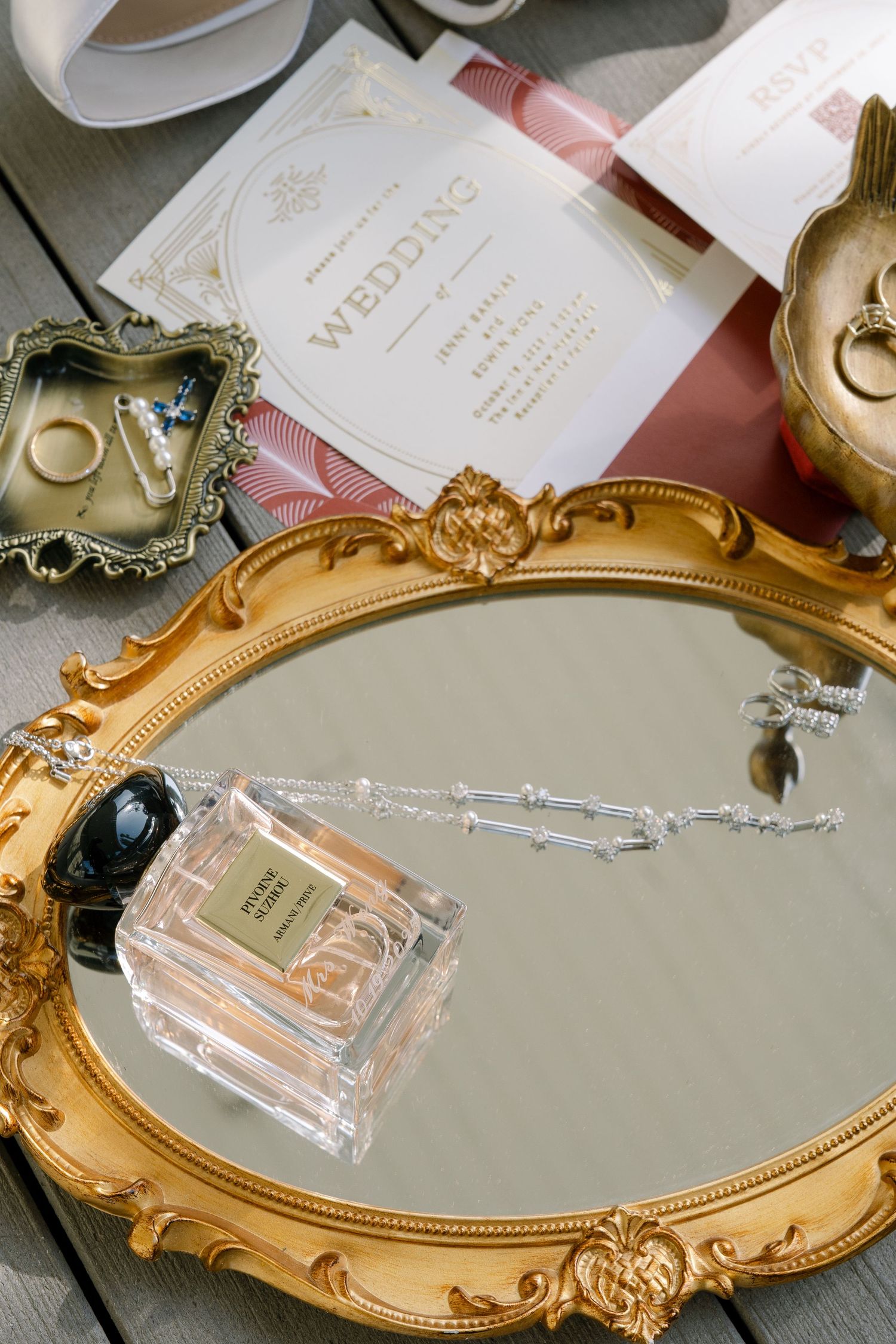 Ornate gold vintage mirror with perfume bottles and wedding details elegantly arranged.