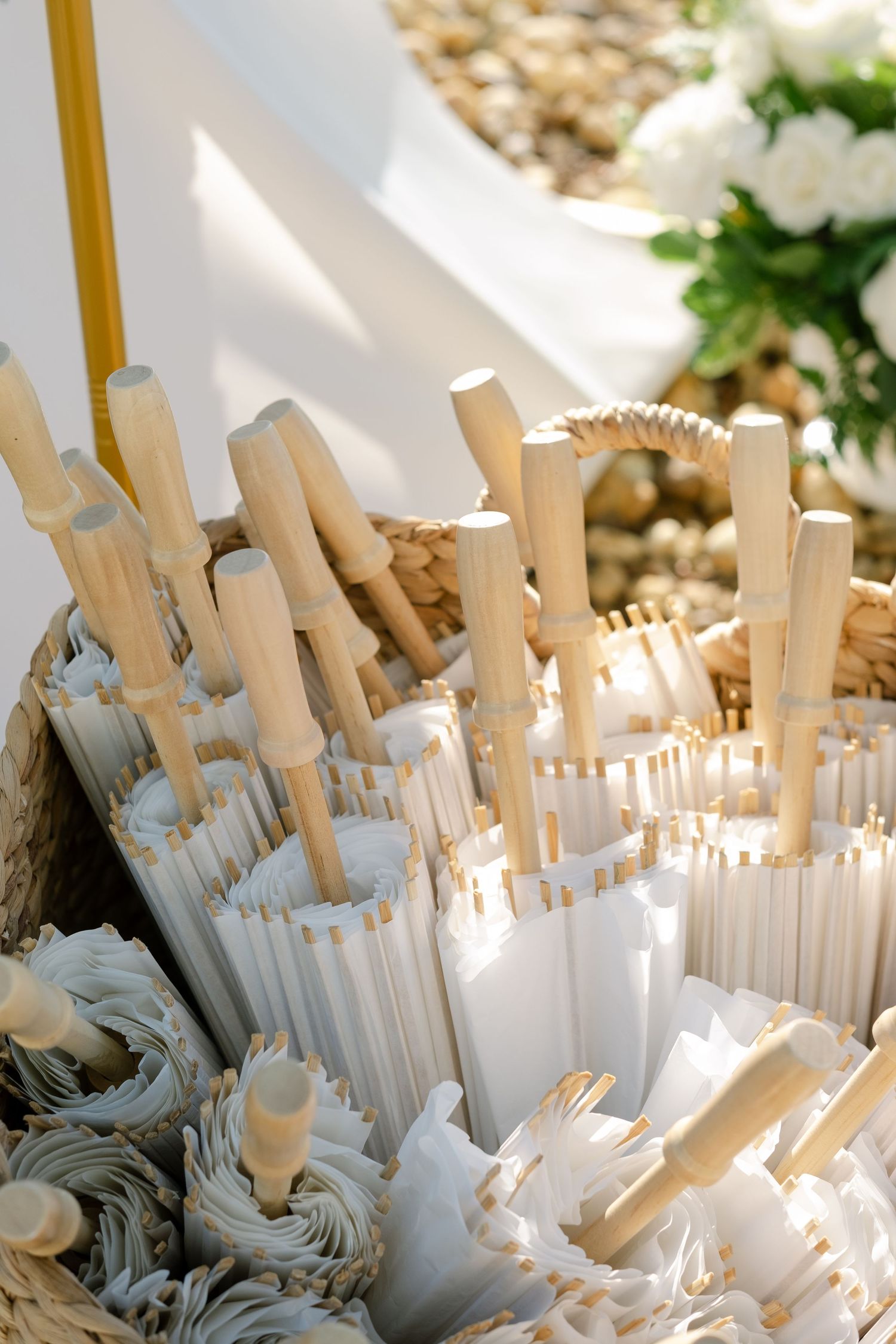 Wedding parasols and paper umbrellas arranged in decorative display at outdoor ceremony.