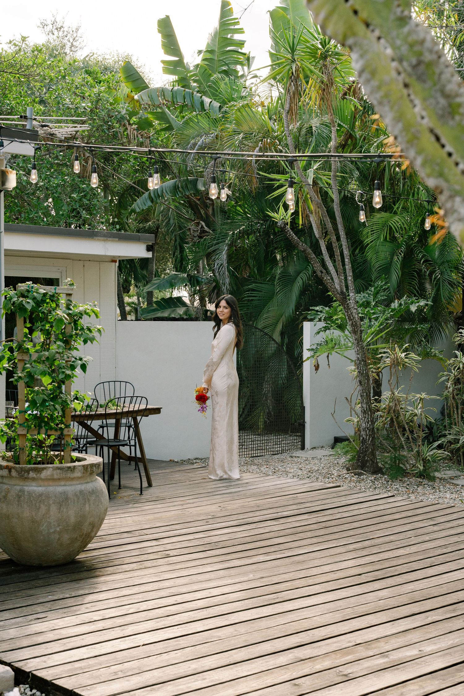 A wooden deck patio area with tropical landscaping and decorative garden furniture.
