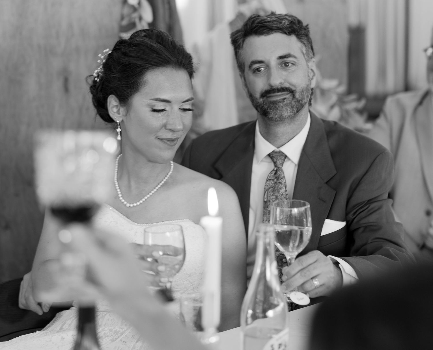 Wedding reception guests at table sharing conversation and laughter while raising wine glasses together at formal dinner party.