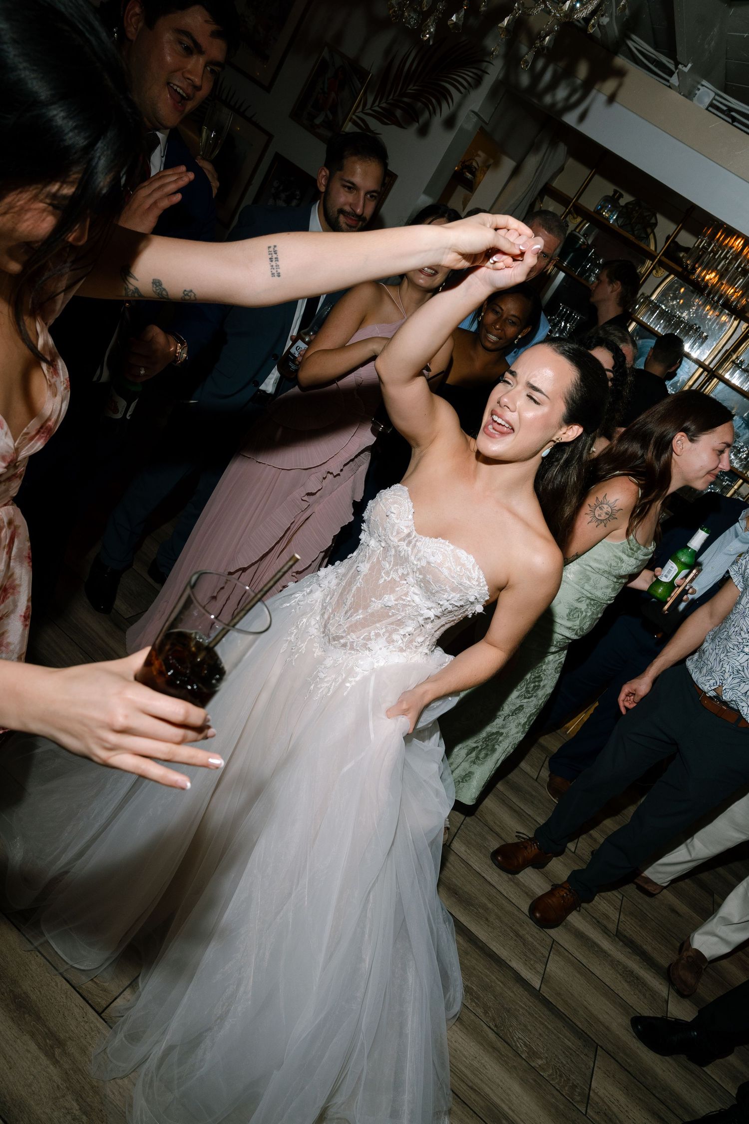 Bride in a tulle gown dancing joyfully with guests at her lively wedding reception.